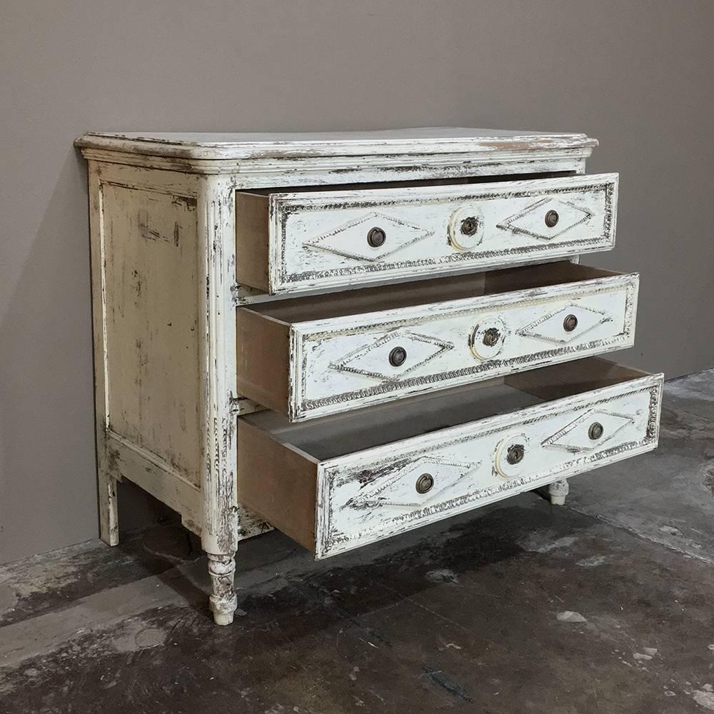 Featuring a lovely distressed finish, this handsome early 19th century Country French  Directoire painted Neoclassical commode displays its origin during the Directoire period, when France was struggling between a monarcy, an Empire and a republic,