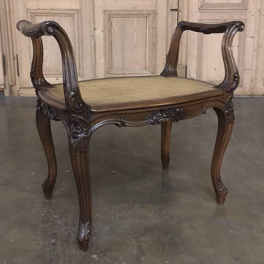 19th century French Louis XV solid walnut arm bench or stool was beautifully hand carved from the finest wood in Europe, with graceful, naturallistic form and scrollwork, floral and foliate carvings all around. Supported by four elegant cabriole