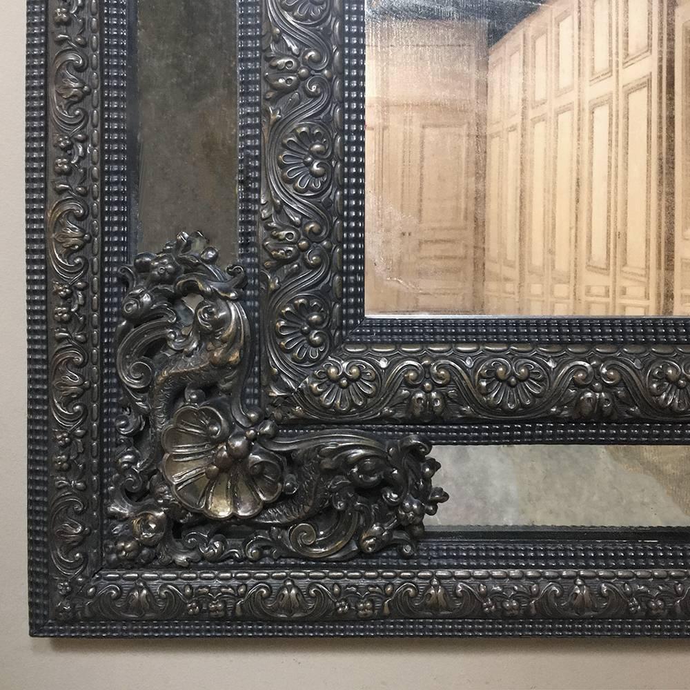 19th century Grand French embossed brass Baroque mirror features an intricately embossed frame with side mirror panels embedded in the design, and a lovely patina that has evolved over the past century! Stylized dolphins, shells, and elaborate