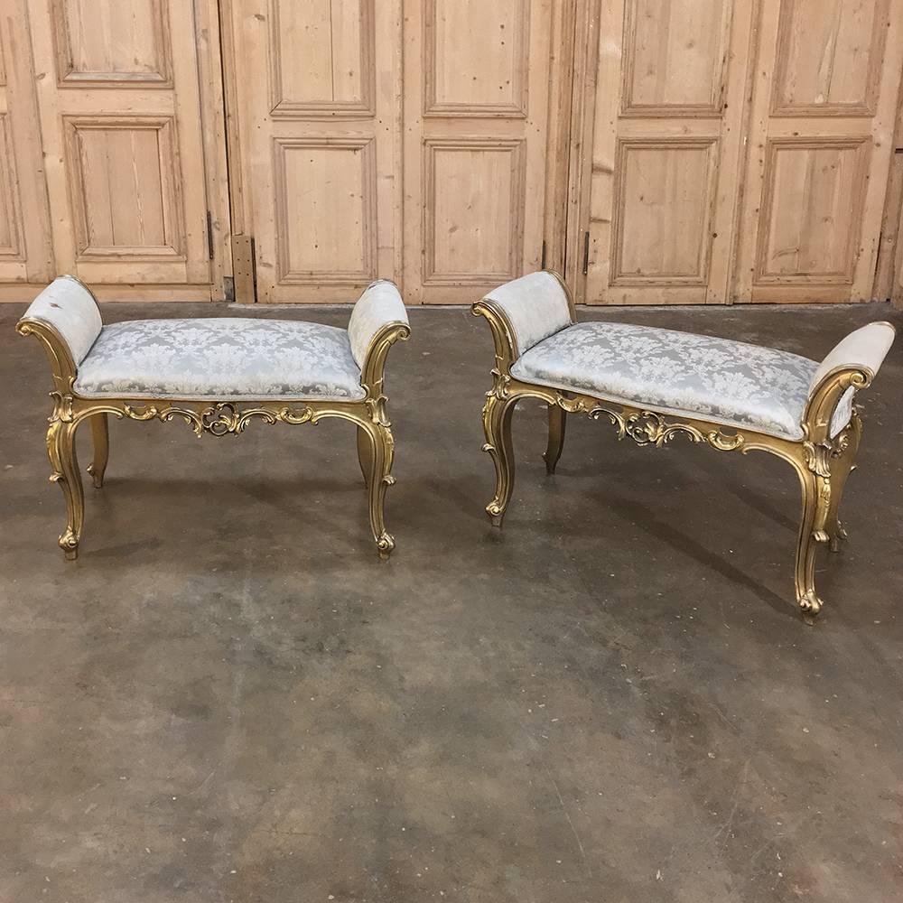 Pair of antique Italian Baroque giltwood arm benches boast the elegant scrolled framework definitive of the style, with hand-carved artistry appearing all around, especially on the graceful cabriole legs and the intricately shaped apron. Armrests