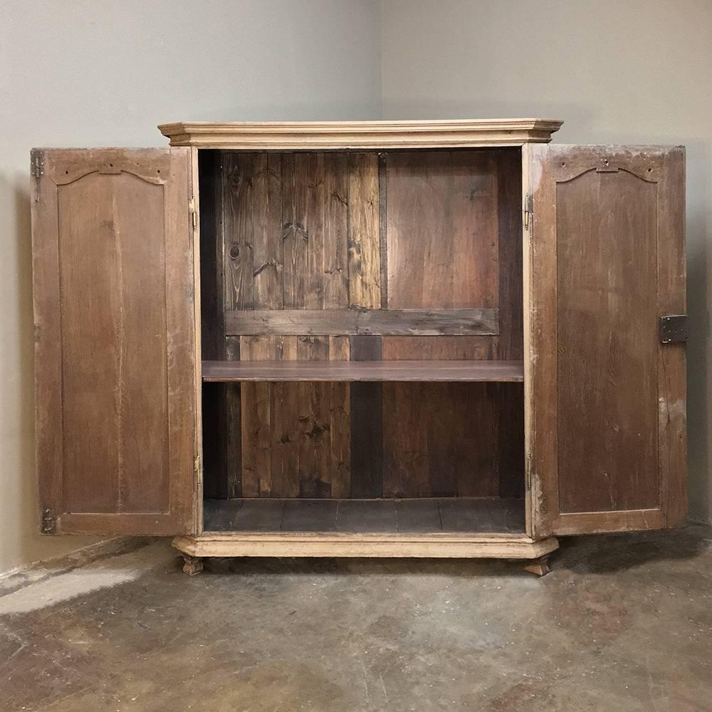 Early 19th century French Regence stripped oak armoire features clean lines enhanced by elegant carvings at the top, mitered corners and subtle molded detailing. Doors open wide to accommodate just about any activity or function you can think of.