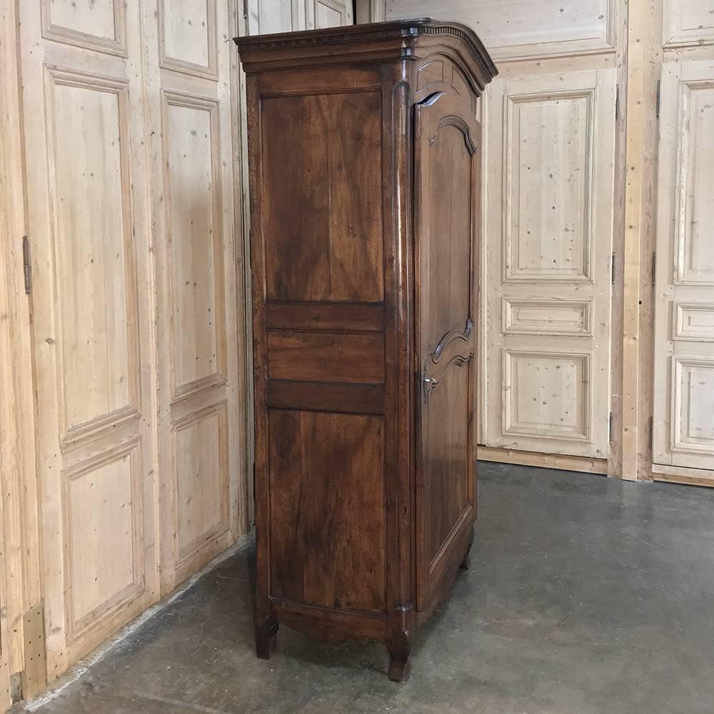 18th century Country French fruitwood bonnetiere represents the essence of the breed, with tailored lines accentuated by the chapeau de gendarme crown above, subtly scrolled panels on the door, and elegantly scrolled lower apron and legs for