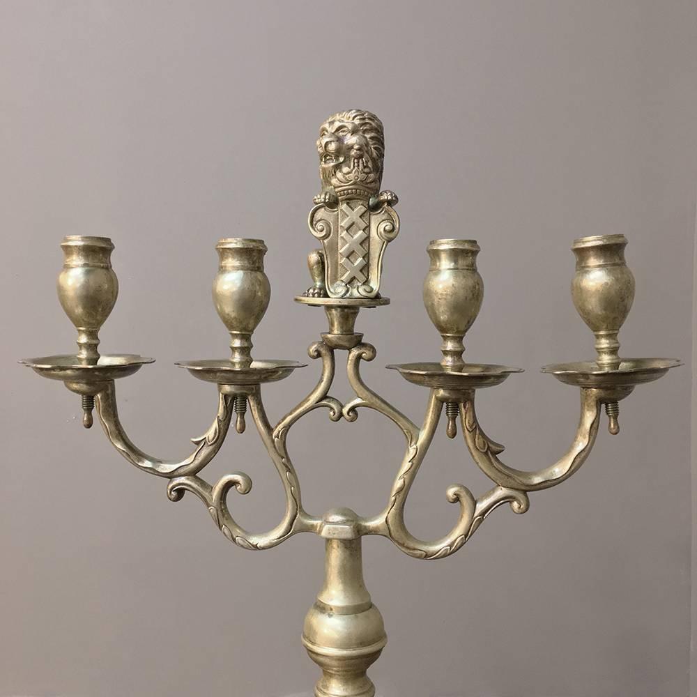 Set of three 19th century bronze candelabra were designed to illuminate a long banquet dining table and feature the family's crest with a lion on top usually representing royal blood in the family tree. Cast from solid bronze, each features strong