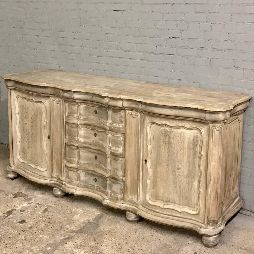 19th century Country French stripped oak buffet features an unusually contoured facade from cornerpost to cornerpost! Spacious cabinets and drawers add functionality galore, and the tailored lines will make this an ideal choice for the casual