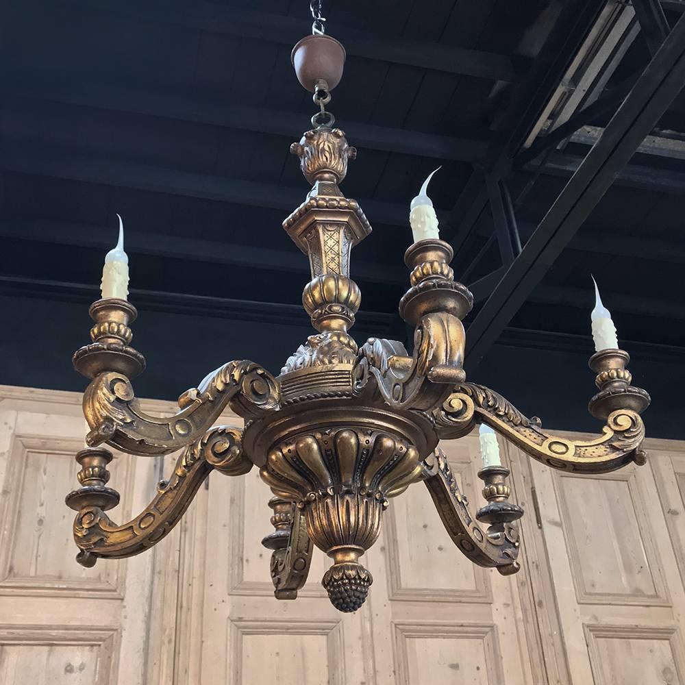 Antique French regence hand-carved giltwood chandelier features an abundance of hand-sculpted detail from the top of the fixture to the pendant finial below. Numerous motifs predominated by the urn shape of the central shaft and acanthus plume