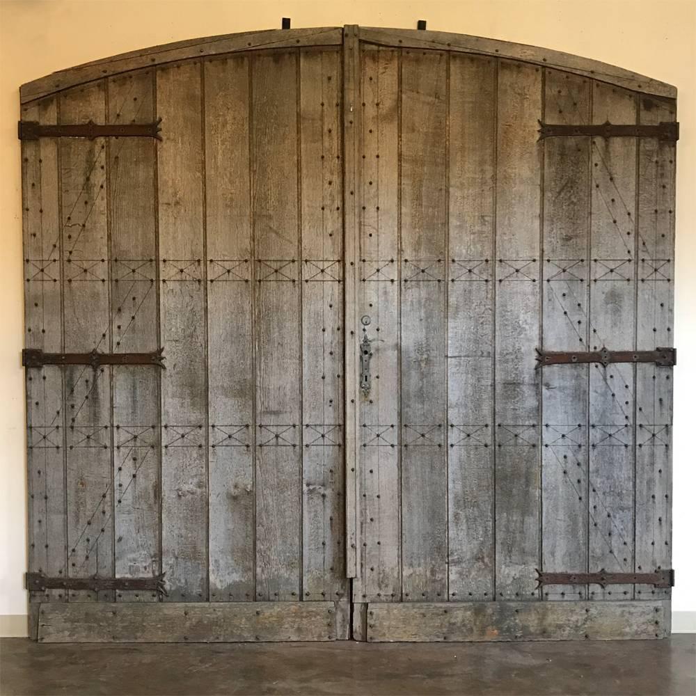 Grand 18th century oak and forged iron barn doors were handcrafted for a gracious courtyard in an expansive manoir in the Rhone valley. Reinforcing truss work on one side (inside) was hand-nailed with hand-forged nails matching the gargantuan forged