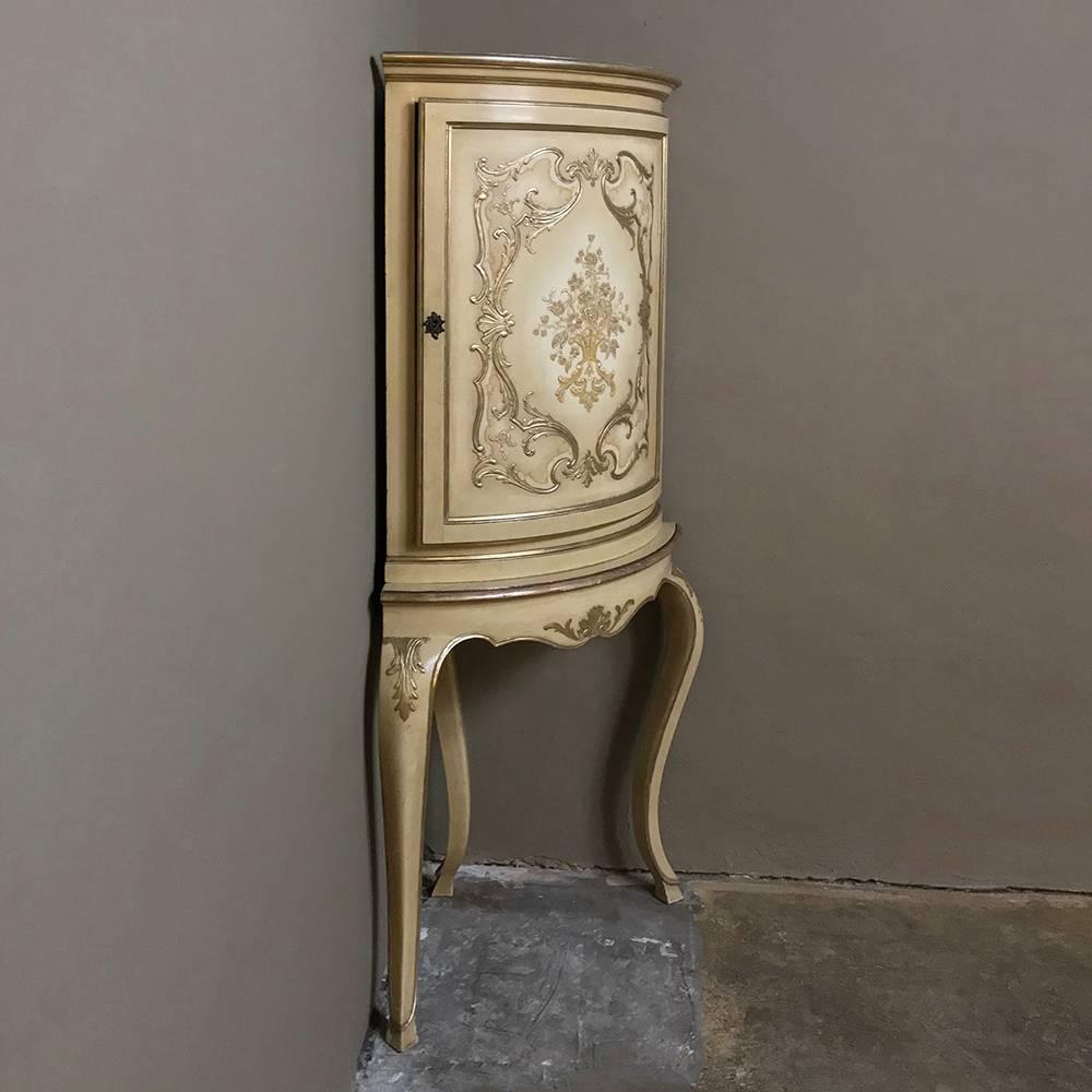 Antique Italian Baroque painted corner cabinet features a bowed facade carved and hand-painted to perfection on a neutral beige background painted finish that has achieved a lovely patina over the decades. Gold highlights add a special Italian