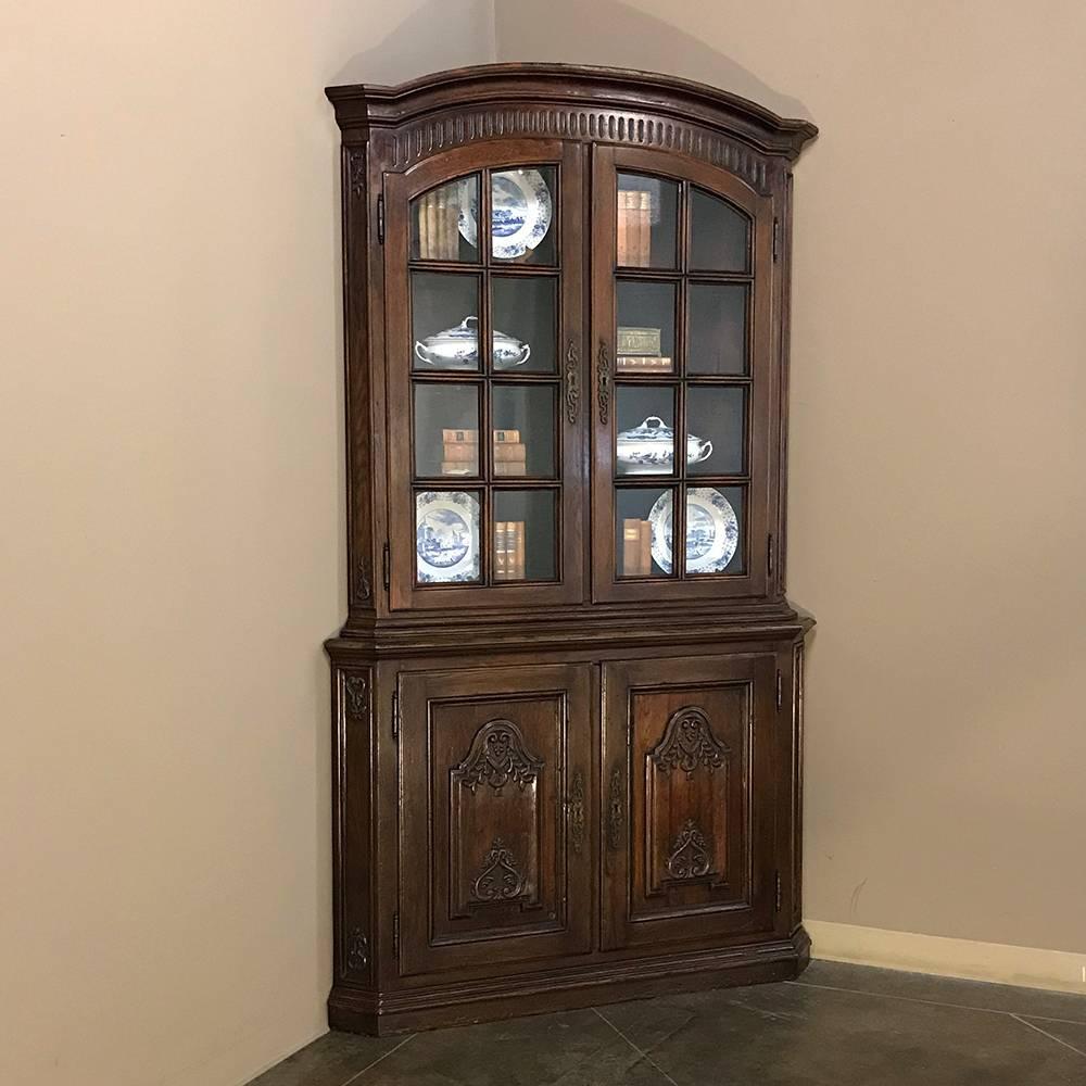 19th century Country French corner bookcase is a rare find, indeed! Sporting a subtly arched crown atop the 16 panes of glazed doors above, it has a neoclassical design in the lower cabinet below which holds surprising storage for a corner