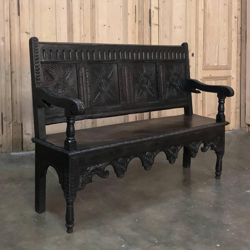 18th century Brittany Country French hall bench features Renaissance-inspired hand-carved embellishment over every square inch of surface! Designed to provide comfort to callers in the days before telephones, it features a slightly canted seatback,