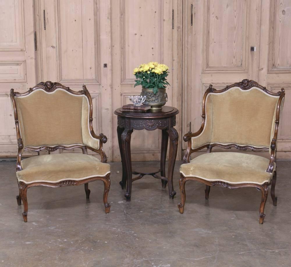 This absolutely gorgeous pair of 19th century French Regence style Bergères (Armchairs) were hand-carved from select French walnut during the 19th century with charming winged cherubs! Serpentine shaped backs and seats rest upon elegantly shaped