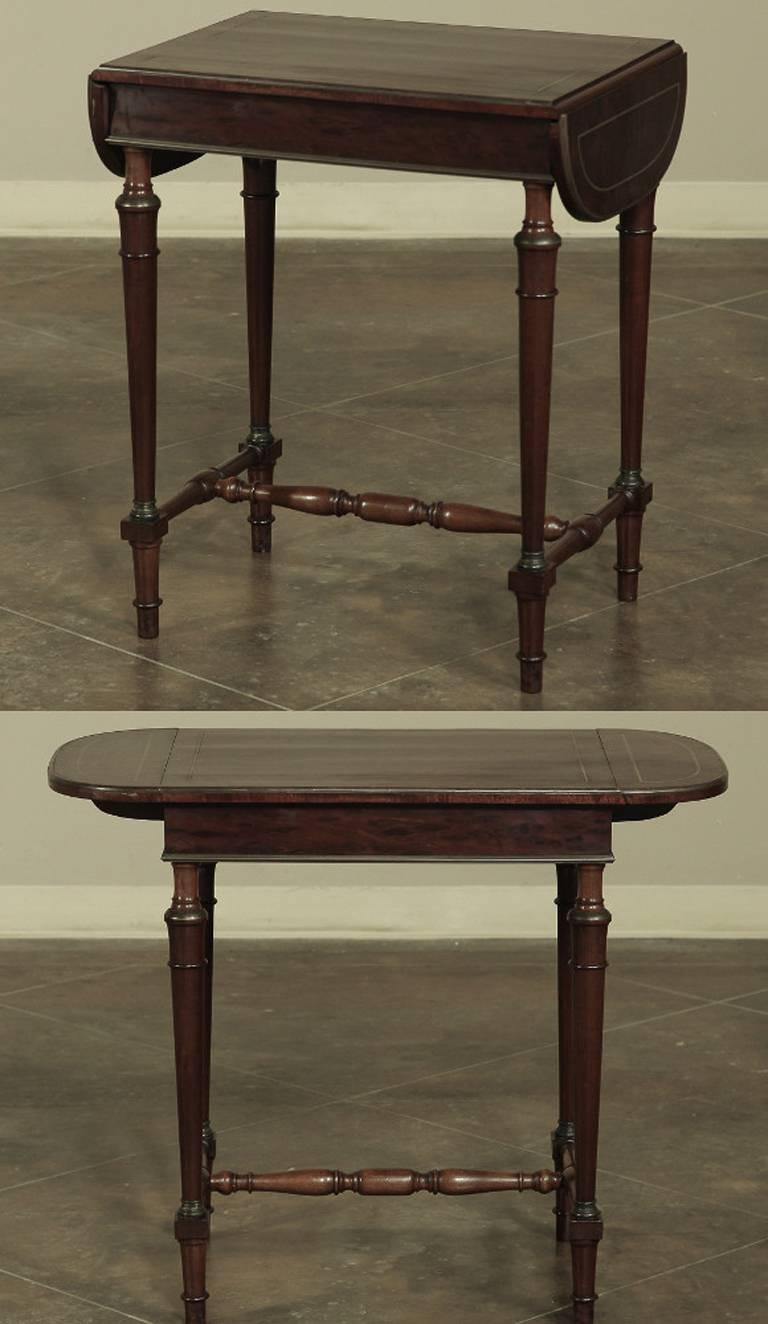 Gorgeous 19th century French bronze inlay drop-leaf mahogany occasional table is as versatile as it is elegant. Crafted during the early Napoleon III period with brass inlay around the edges, and tapered column legs, it has a lightweight appearance