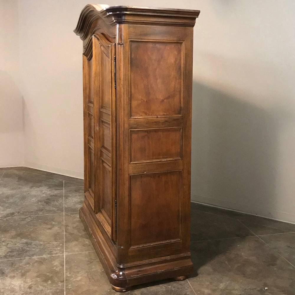 19th century country French walnut armoire represents the essence of the genre, with a bold chapeau de gendarme cornice overlooking the broad, facing archwork of the door frames below. The doors open wide to reveal a grand unencumbered interior