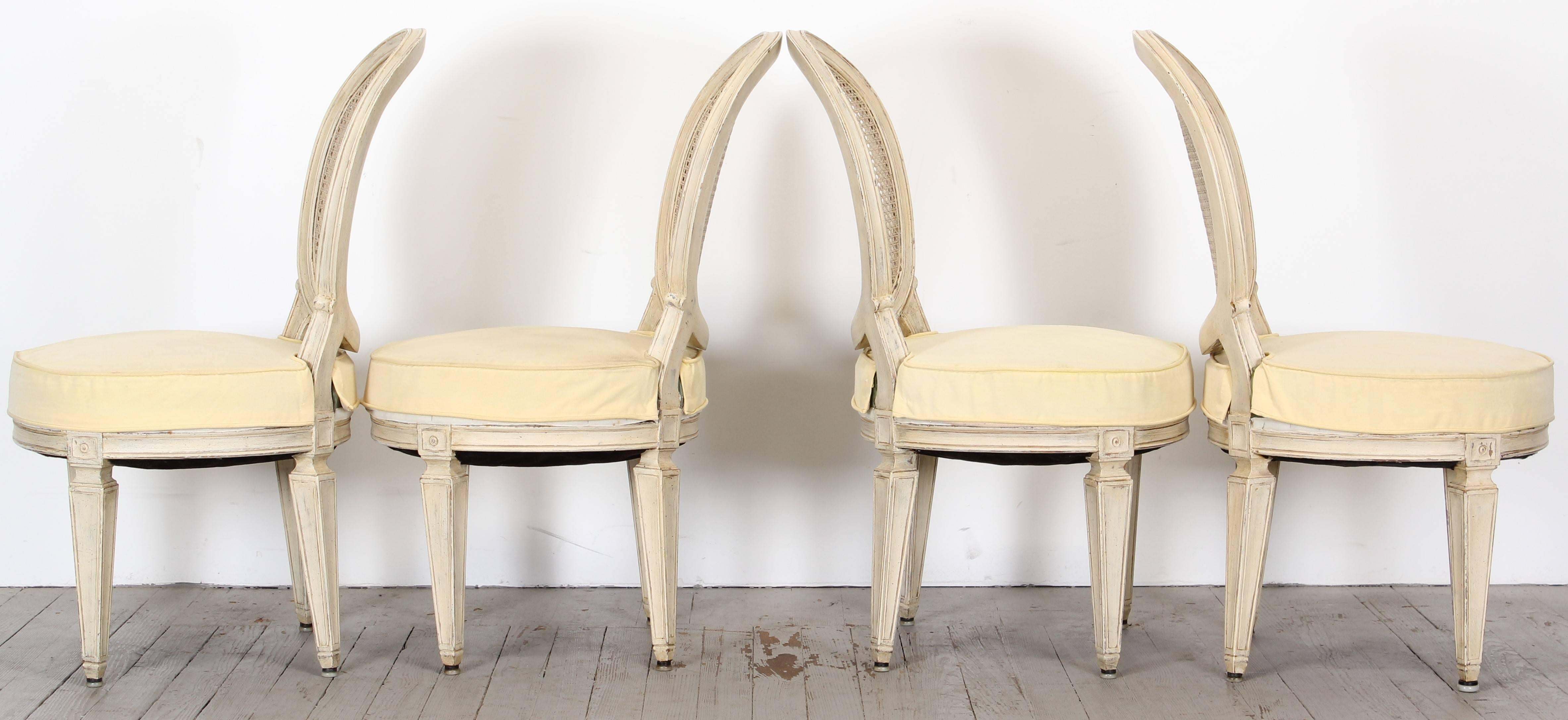 A fabulous large-scale dining set of four Louis XVI style painted chairs in the manner of Jansen. The coil spring seats are very wide and comfortable to sit in as far as French side chairs are concerned. Great painted matte white finished chairs