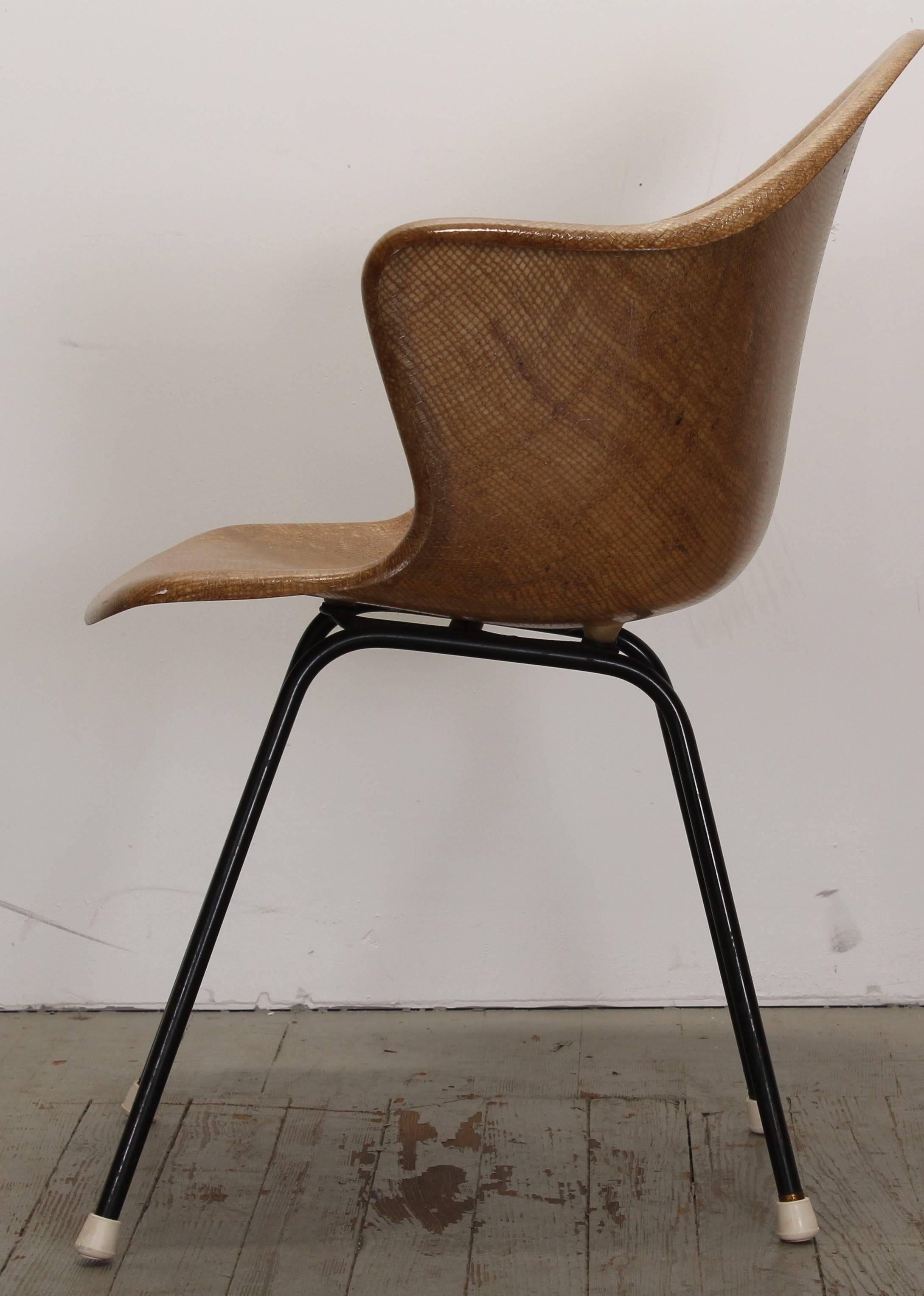 A great Mid-Century Modern armchair attributed to Luther Conover. The shell has a burlap design which was molded into the fiberglass. The chair is a light brown to golden wheat color accented by black metal legs. The feet are not original.