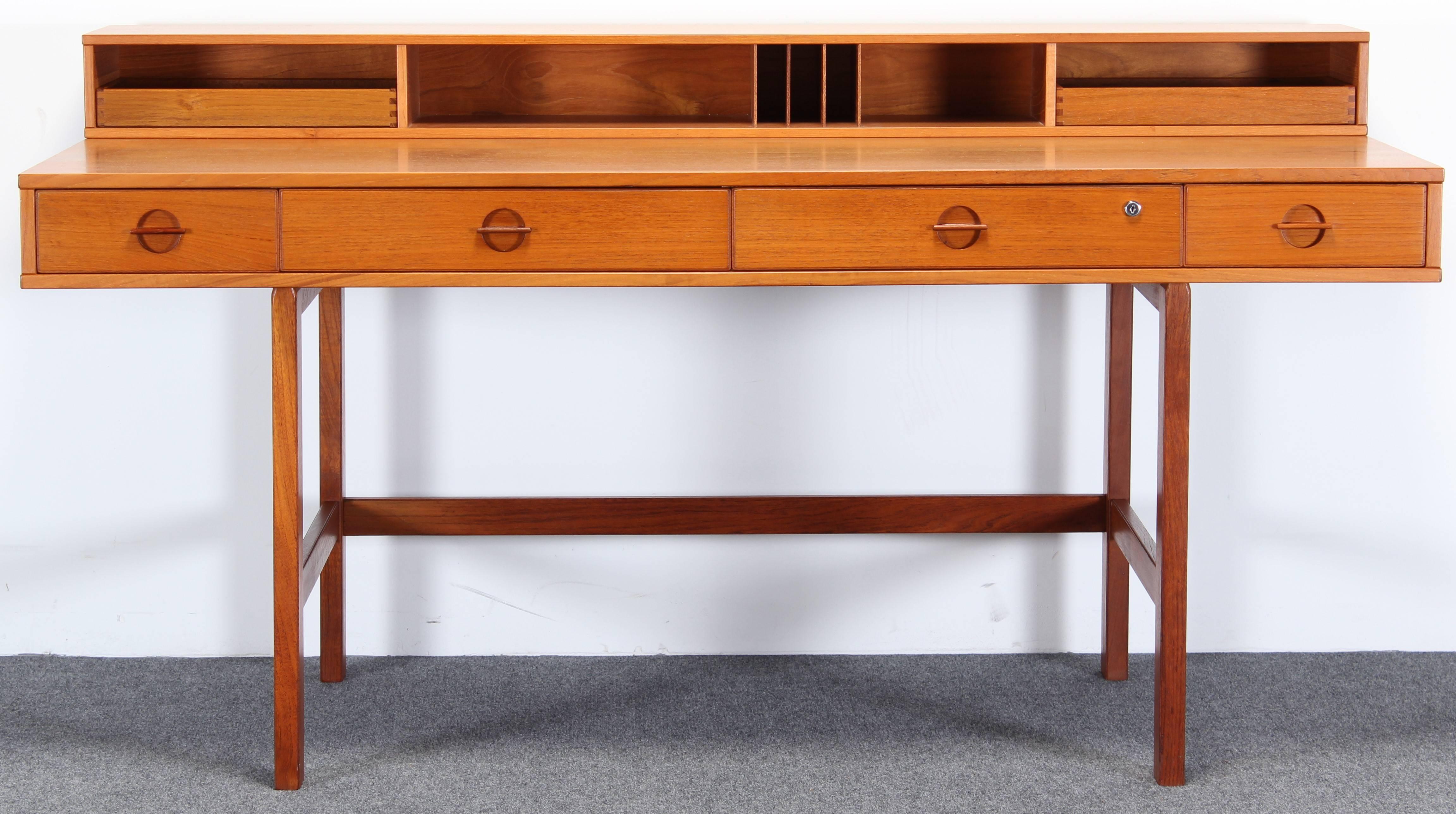 Designed by Peter Lovig-Nielsen, sometimes attributed to Jens Quistgaard. Teak wood desk with four drawers, no key for lock, drawer is currently unlocked. Height of flip-top up is 34 inches, depth of desk is 38 inches when flip-top is down. Overall