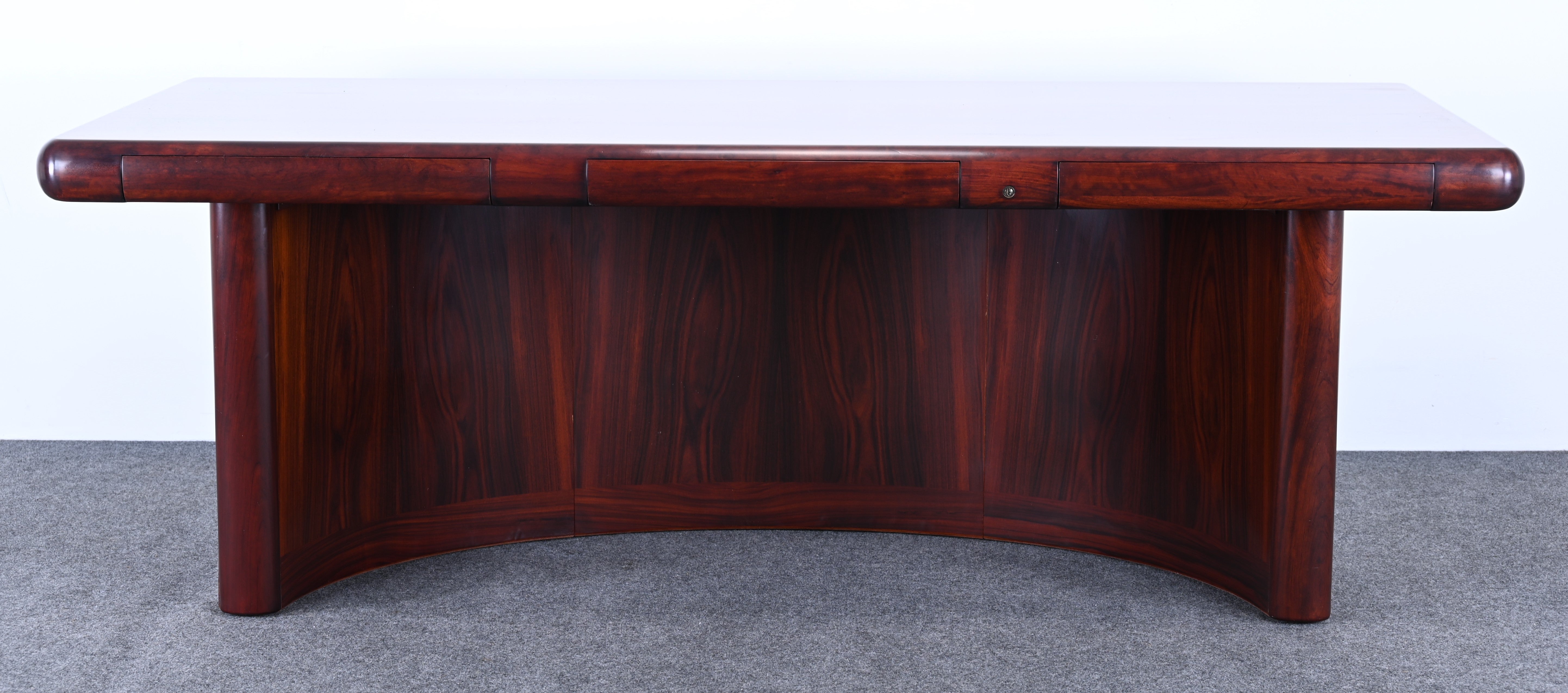 An impressive Mid-Century Modern Danish rosewood executive desk by Dyrlund. The desk has two drawers and a pull-out desktop. The spectacular curved base adds beautiful detail. Would look great in an Executive's work or home office. Structurally