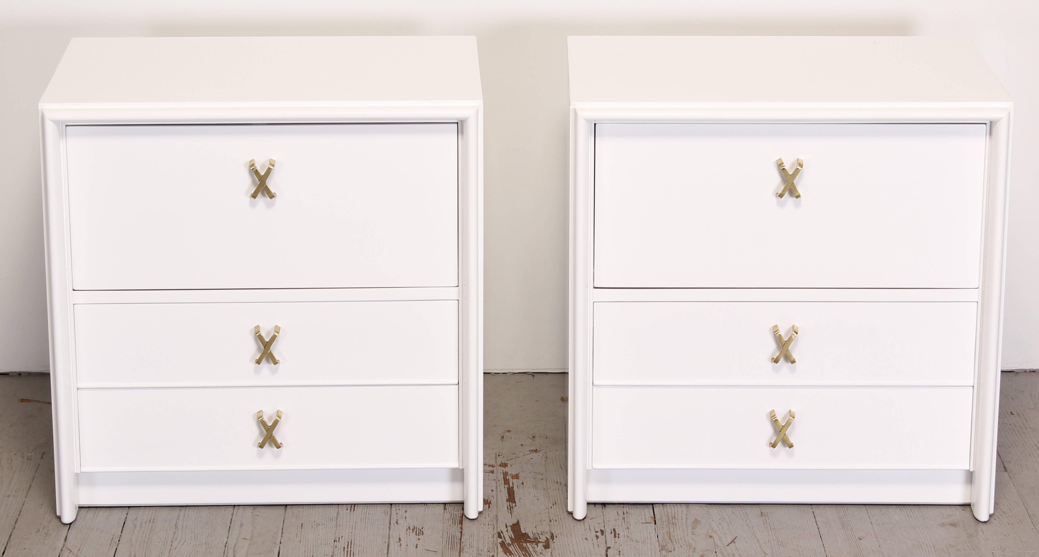 Pair of nightstands with brass X-pulls and white high gloss Italian finish by Paul Frankl. Newly refinished by Alternative Furnishings Inc. Matching dresser available separately. Labeled inside drawer Johnson Furniture Co, American.