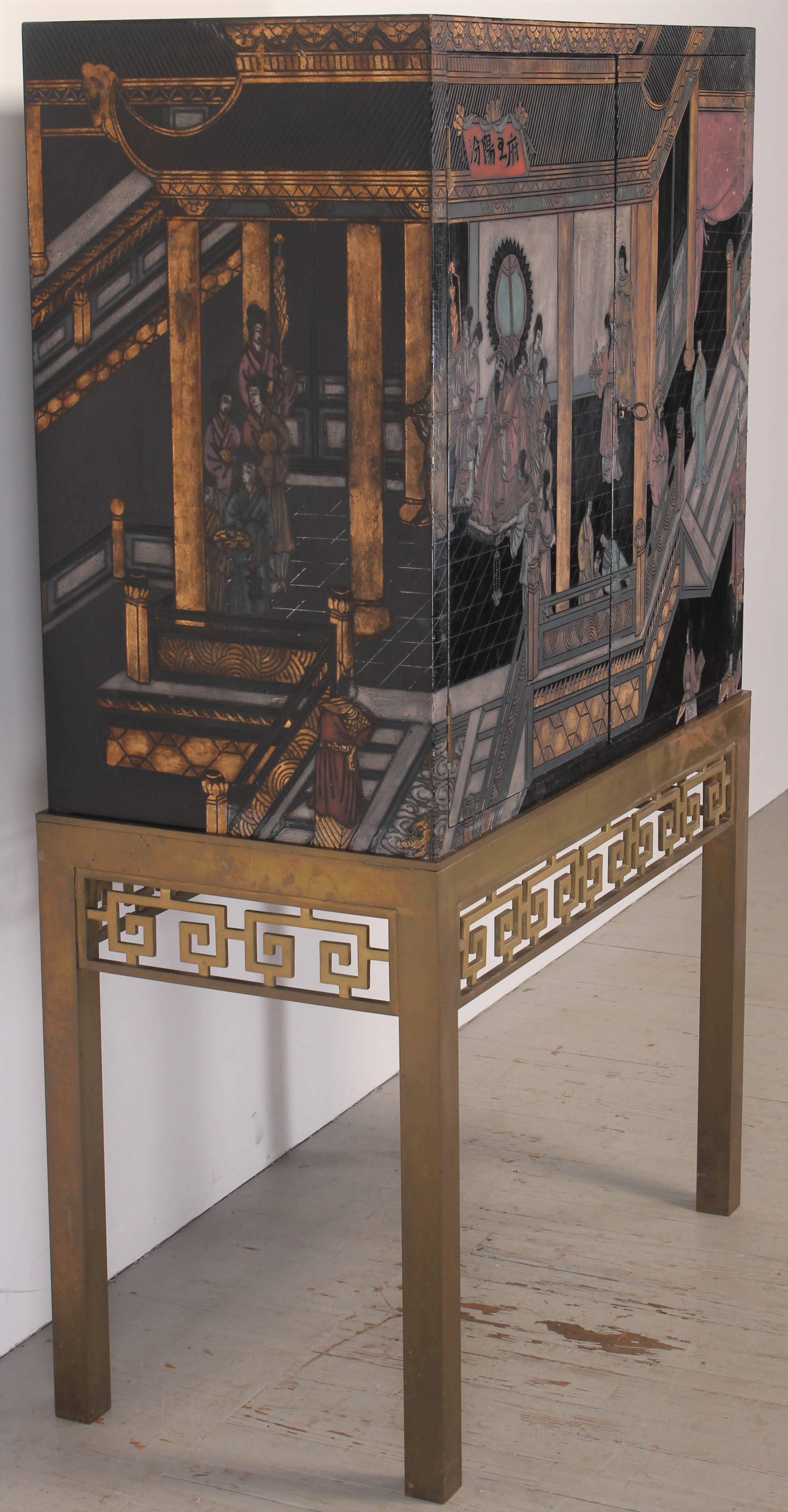 A Chinese style black lacquered cabinet on a solid brass stand. Christie's sold one in 2002 attributing it to Maitland Smith for David Hicks. The hand decorated top cabinet has one adjustable shelf, two doors, one side latched other side key