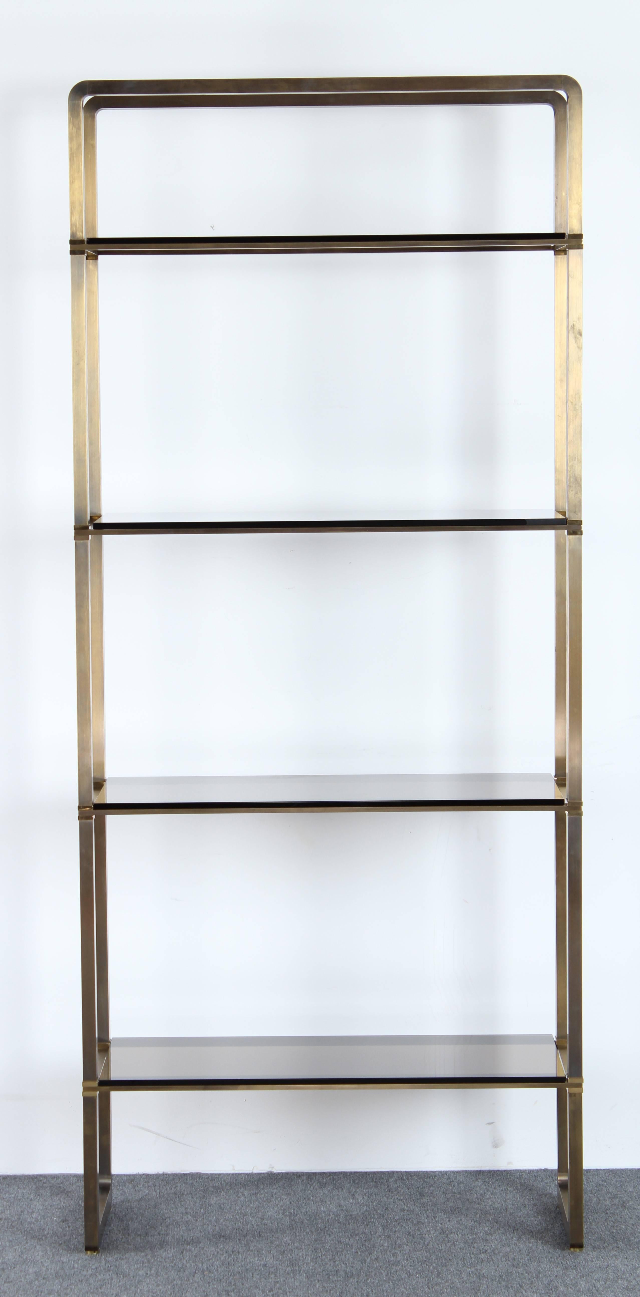 A fabulous Paul M. Jones bronze and glass four-tiered etagere or display shelf with four smoked glass shelves. Solid bronze and brass frame. Versatile and modern. Very good condition with age appropriate wear. Two shelves have minor chips, as shown