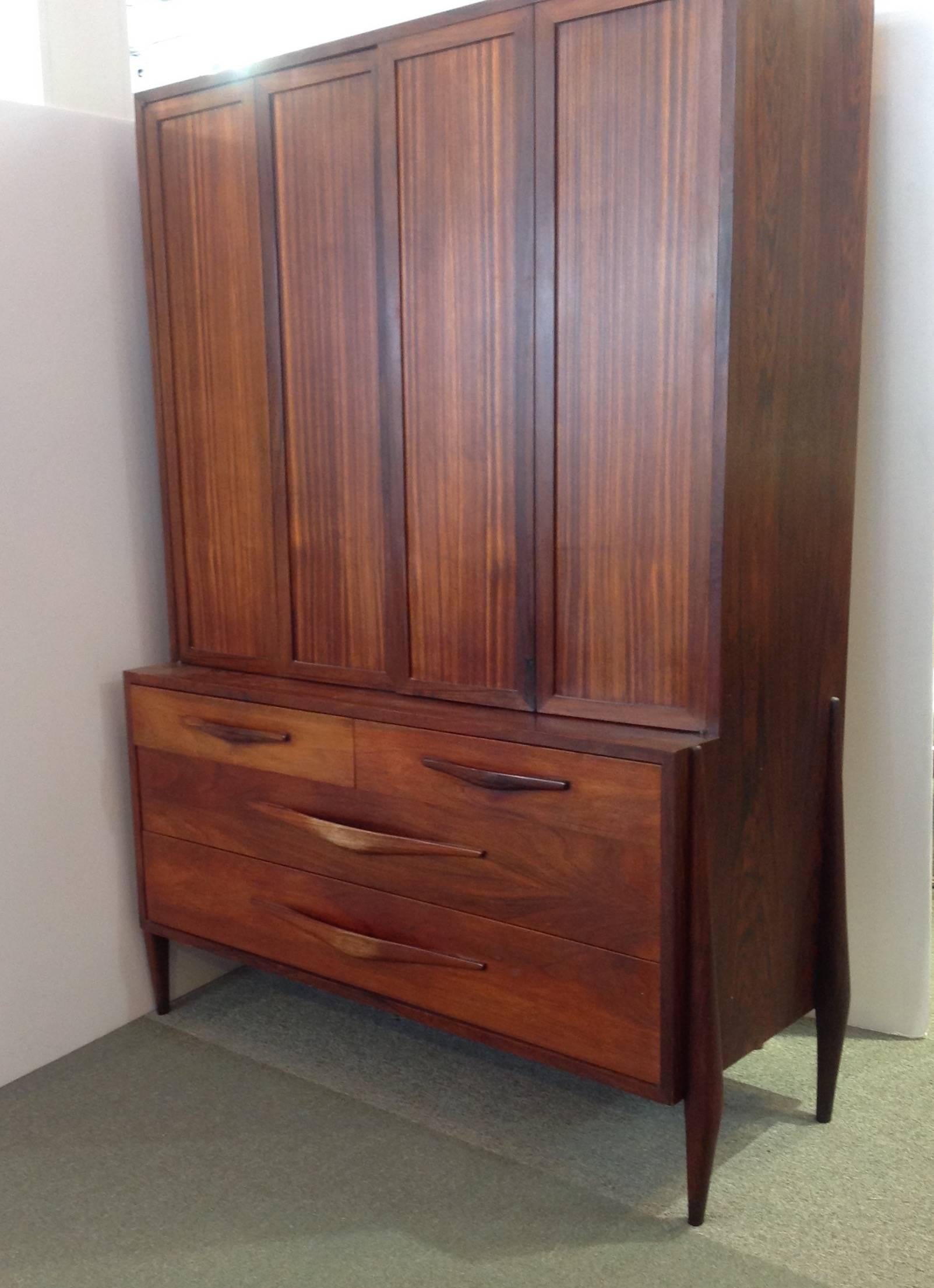 Mid-Century Modern rosewood cabinet made by Pallagi. It has folding doors enclosing three shelves over four drawers. It was probably made in Hungary in the 1960's.