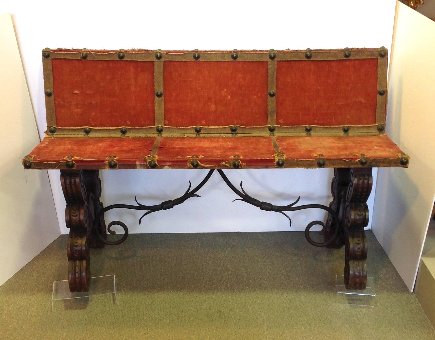 Antique Spanish hall bench with an iron ornamental stretcher, red velvet seat and carved wooden legs. Made in Spain.Circa 19th century.
