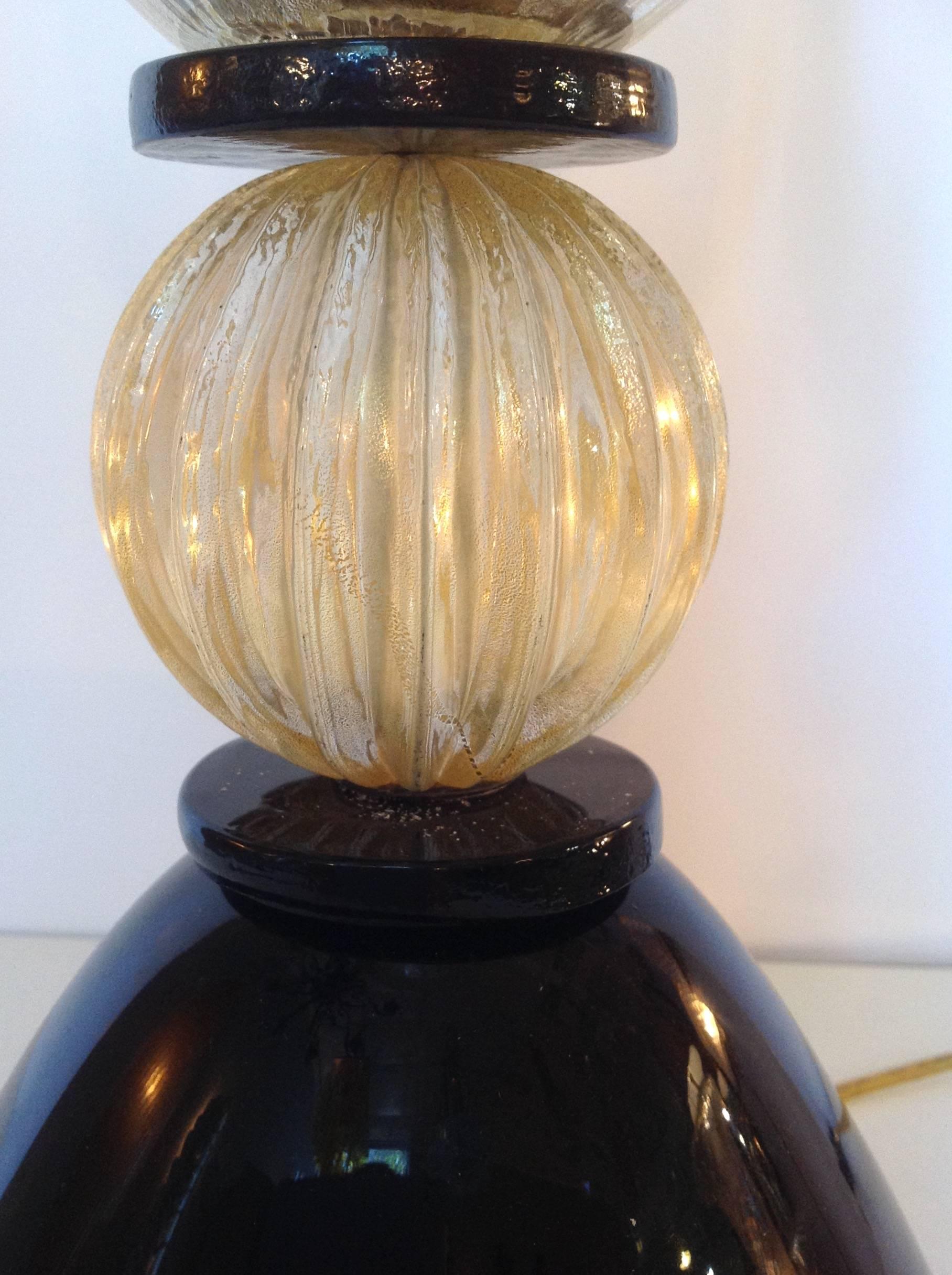 Pair of midcentury Murano glass urn lamps with gold leaf in clear glass on black glass bases. The melon shaped balls on the bases are gold infused. They were made in Italy in 1960.