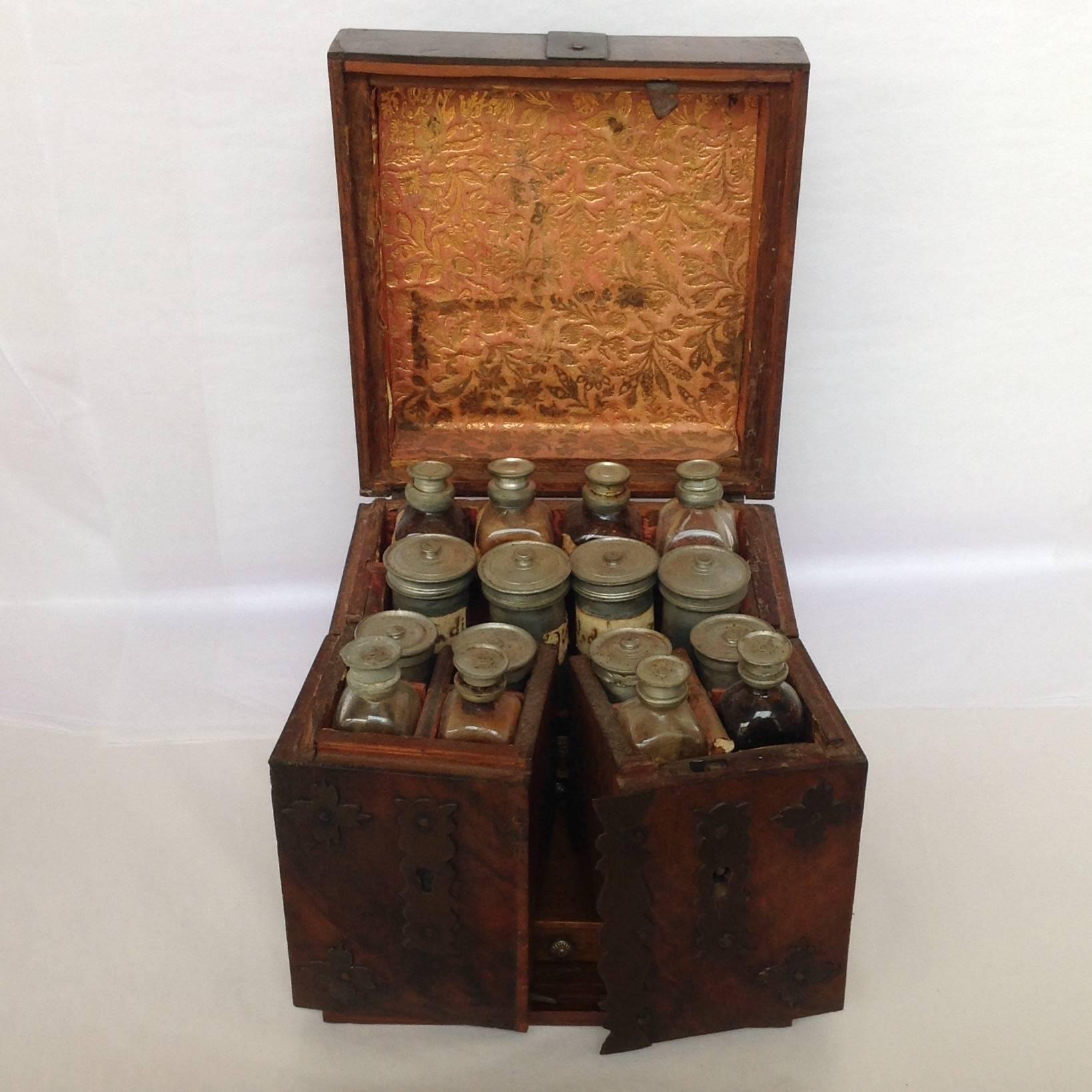 Portable Dutch Apothecary cabinet with a burled walnut self-locking case. The lid lift and the side cabinets swig out. There are small drawers in each cabinet with unidentified black specimens. There are eight original glass bottles with pewter tops