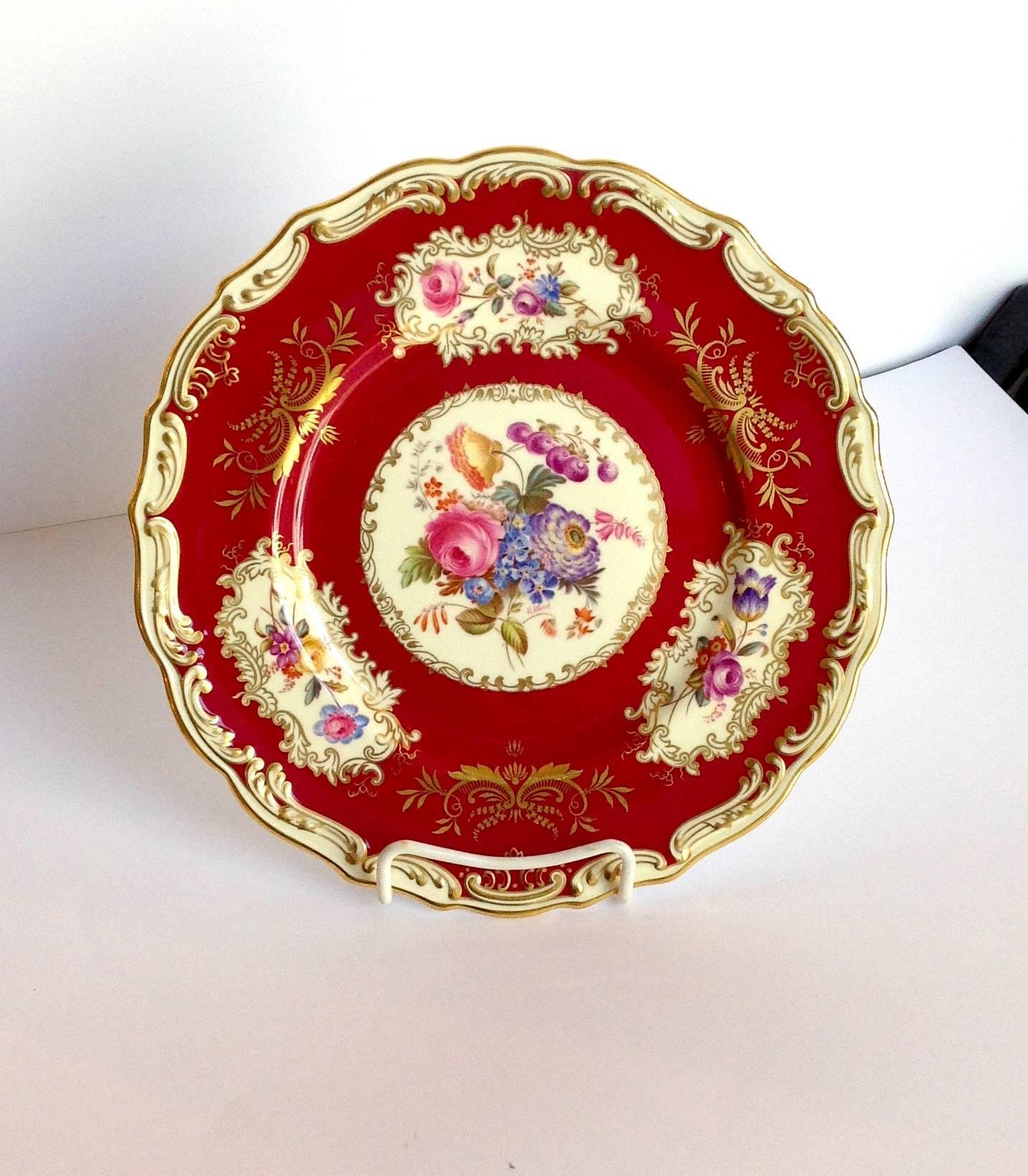 Two dozen Copeland Spode plates with hand-painted floral decoration on crimson ground with raised gilt edge by R. Wood. They are signed on the front in the middle floral scene. Marked on the back 'Spode Copeland China England Spode period 1790-1820,