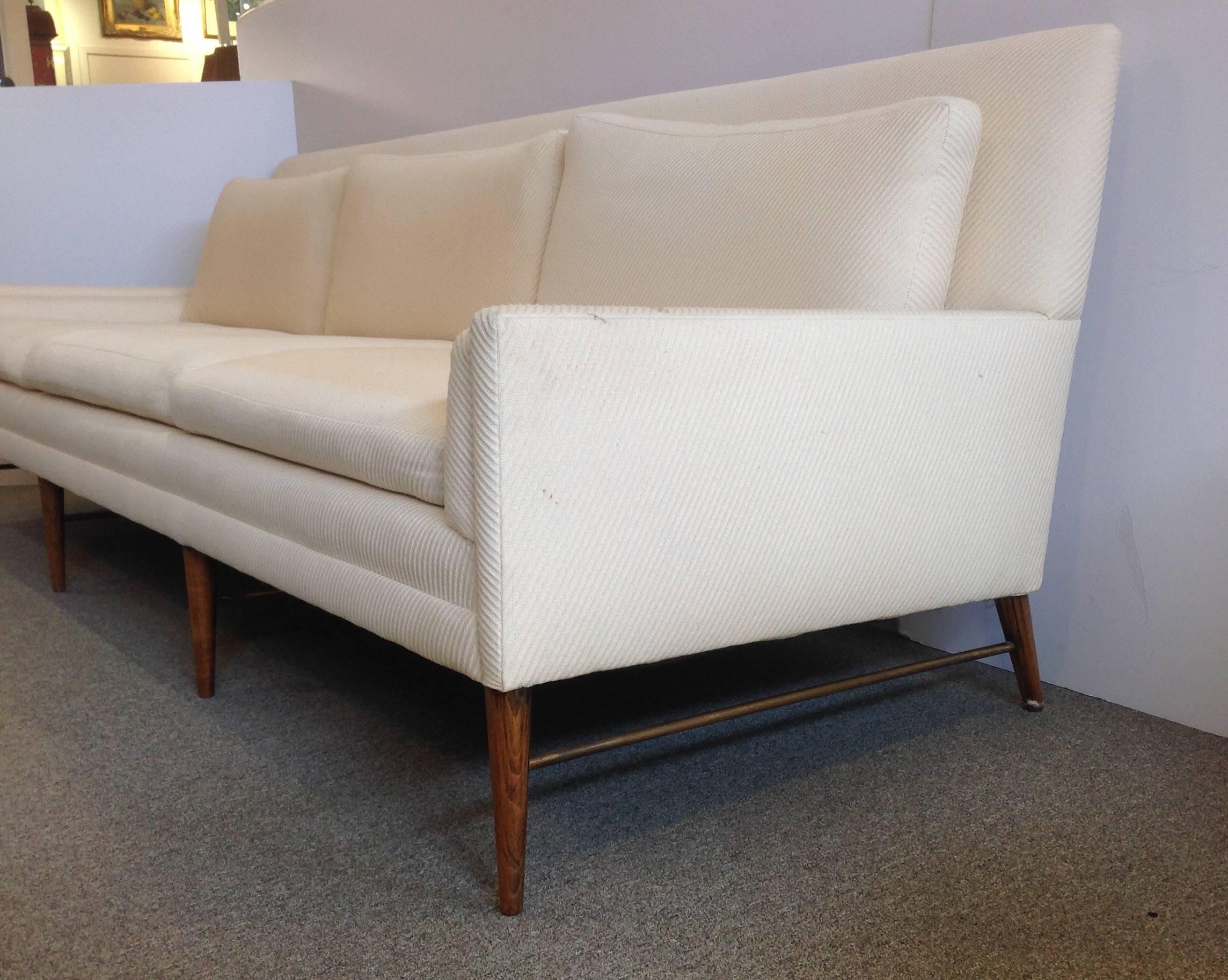 Rare long Paul McCobb Directional sofa on a stretcher base. This extra-long sofa has eight legs with brass rail. The upholstery is a textured off-white with no rips but could be cleaned, circa 1960s. Measures: 96