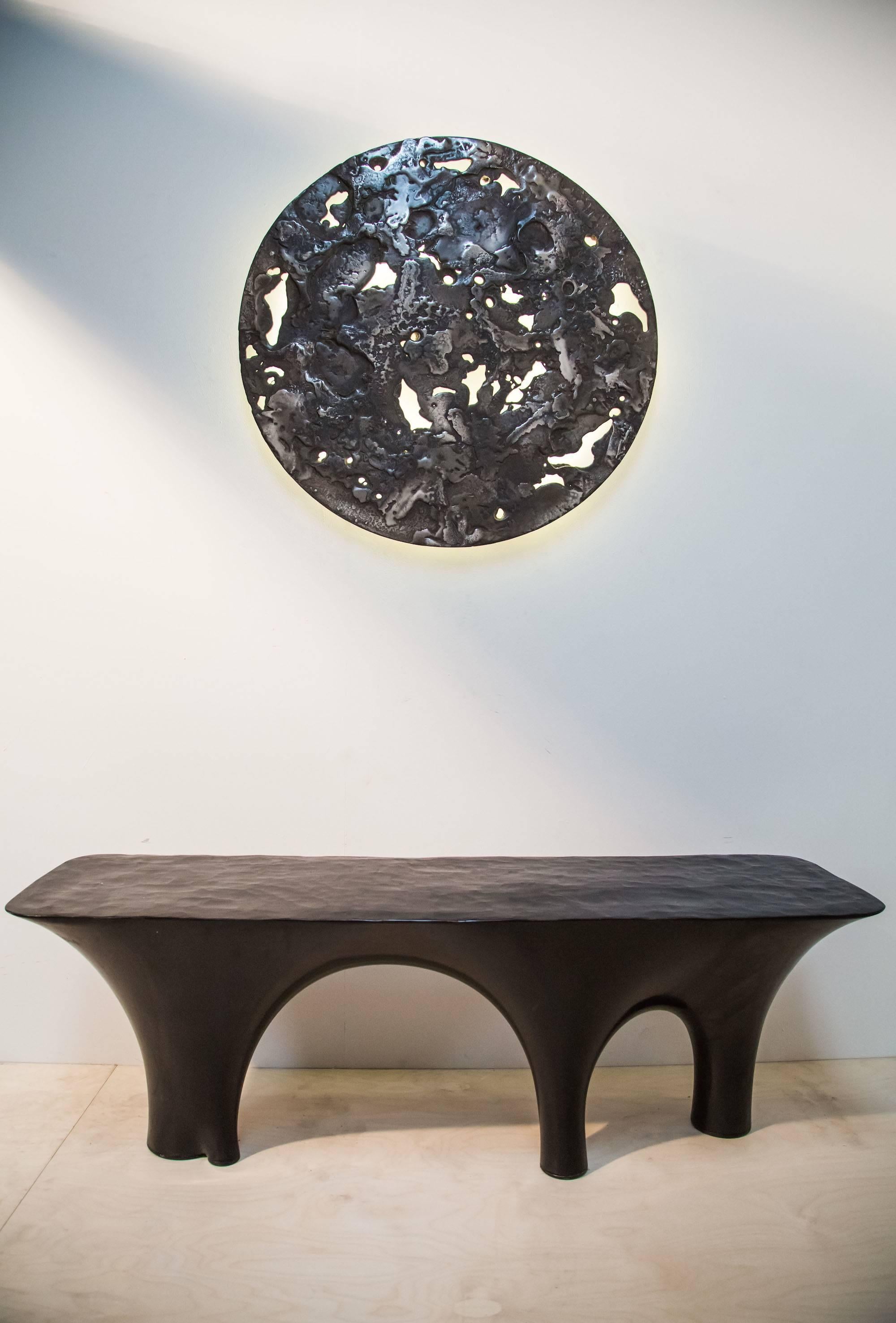 IO moon is a free-form cast pewter disc designed to be wall-mounted and lit from behind by a hidden LED light strip. The images show the piece lit during the day and in a totally dark room. 

Wiring is with 12v dc constant current warm white LED