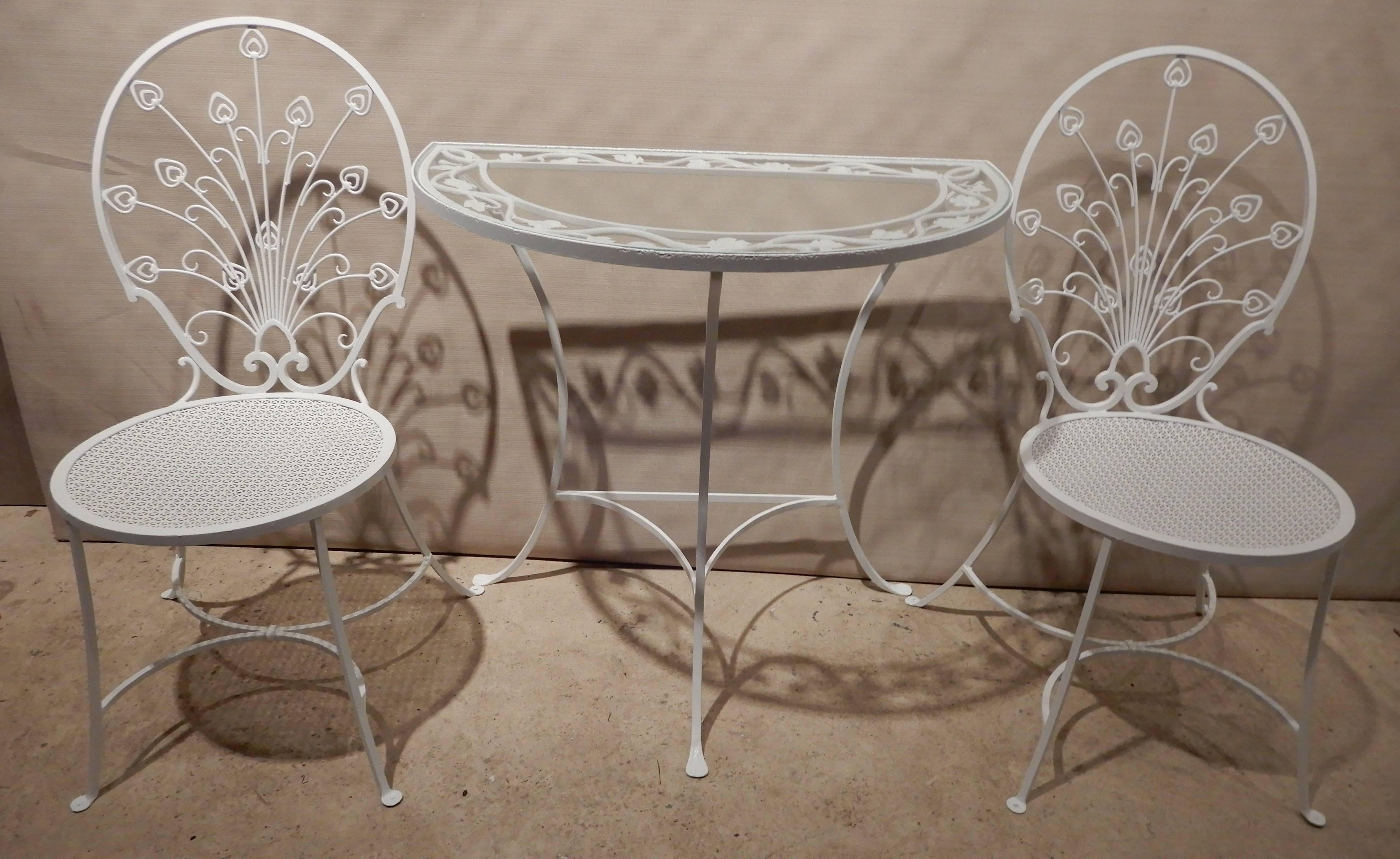 This is a most unique pair of mini wrought iron Peacock chairs en suite with a matching table. They are in the Hollywood Regency style and would work well 
In a foyer or where ever space is an issue. The shape of the back and detail is strongly