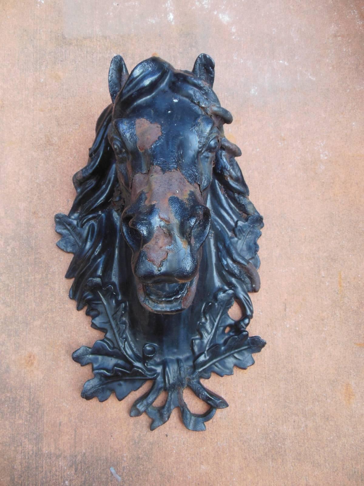 A antique cast iron horse head with excellent detail. The cast iron horse head may have been designed to be mounted on a wall of a commercial stabile or tack shop. The finish of the horse exhibits some paint loss which is also indicative of its age.