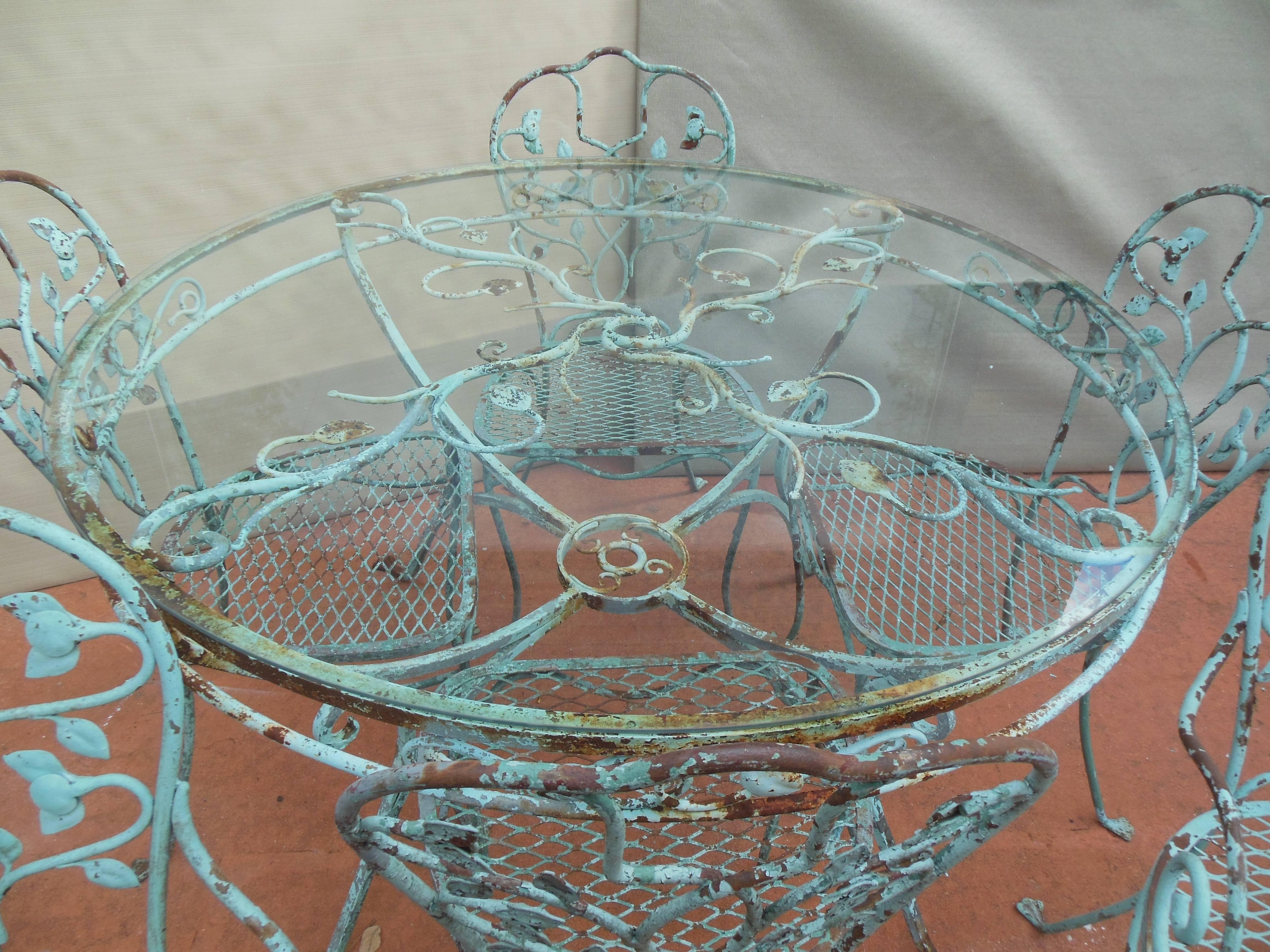 An elaborate wrought iron Salterini Dining Set. The Salterini dining set consists of six chairs, two arm and four sides and a 48 inch round table. The chairs all have detail of leaves and some fruit carvings and are raised on the Salterini paw foot.