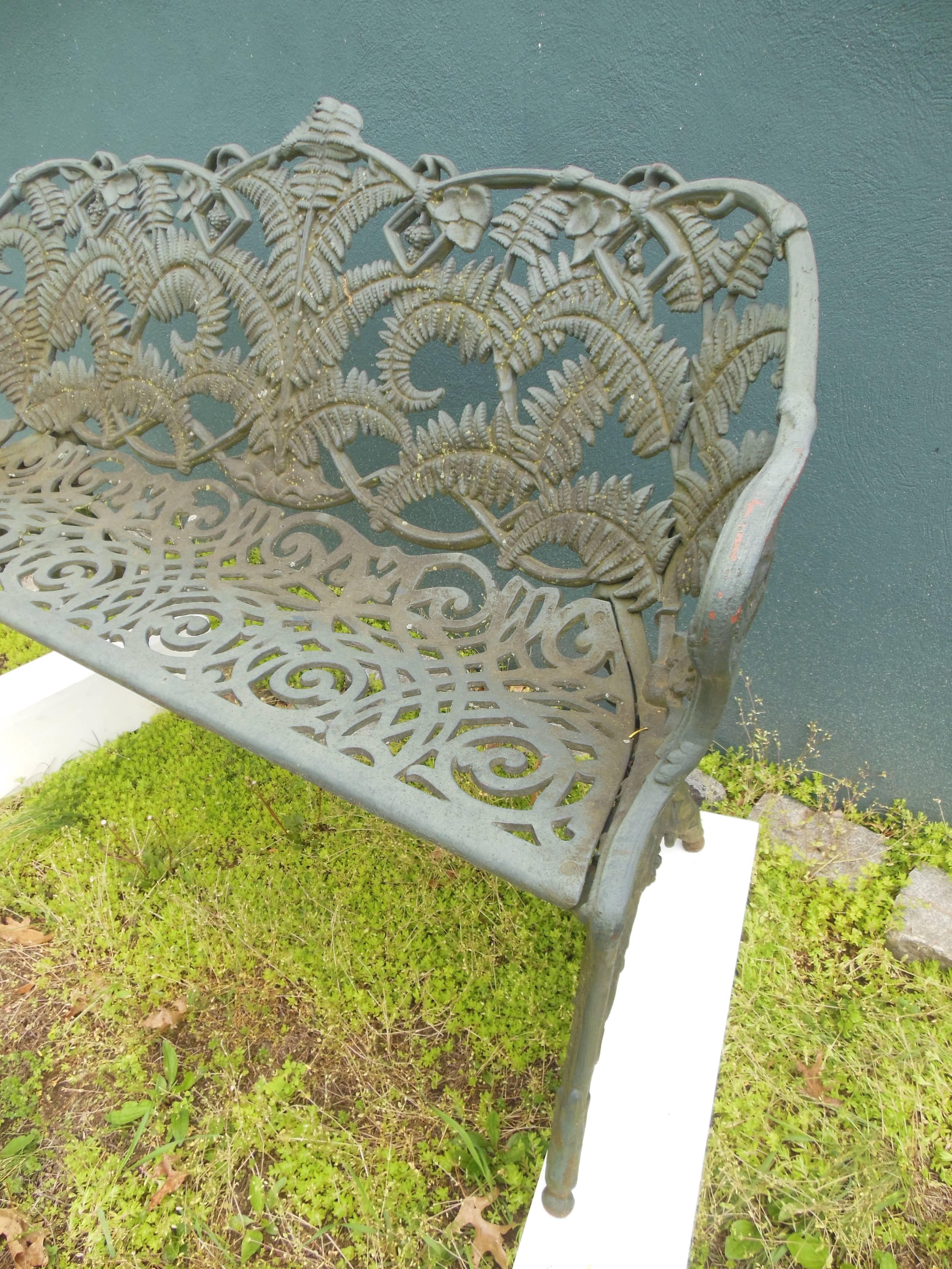 An antique cast iron garden bench in the desirable fern pattern. The detail of the bench with the scroll design on the seat and the back ablaze with the detail of large fern leaves. The measurements on this very heavy cast iron bench differ from
