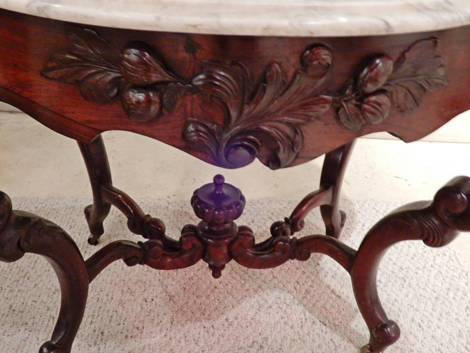 A John Henry Belter Victorian rosewood Rococo Revival centre table. Belter furniture can be seen in most major American Museums. The rosewood Belter table is carved with fruit, vines leaves and flowers, all topped by a white marble top. The S curved