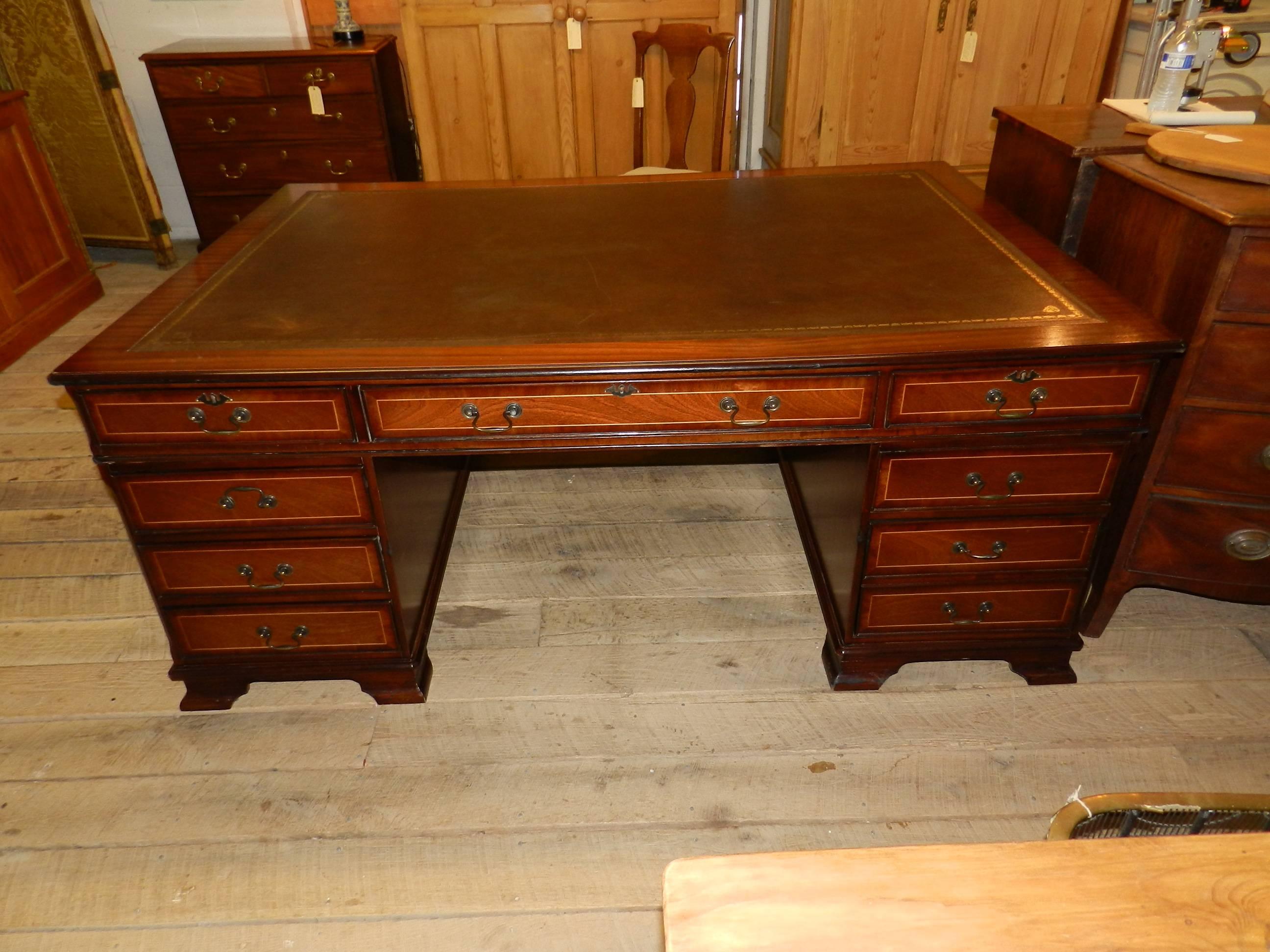 Twin pedestal inlaid mahogany partners desk with inset leather top and brass handles.