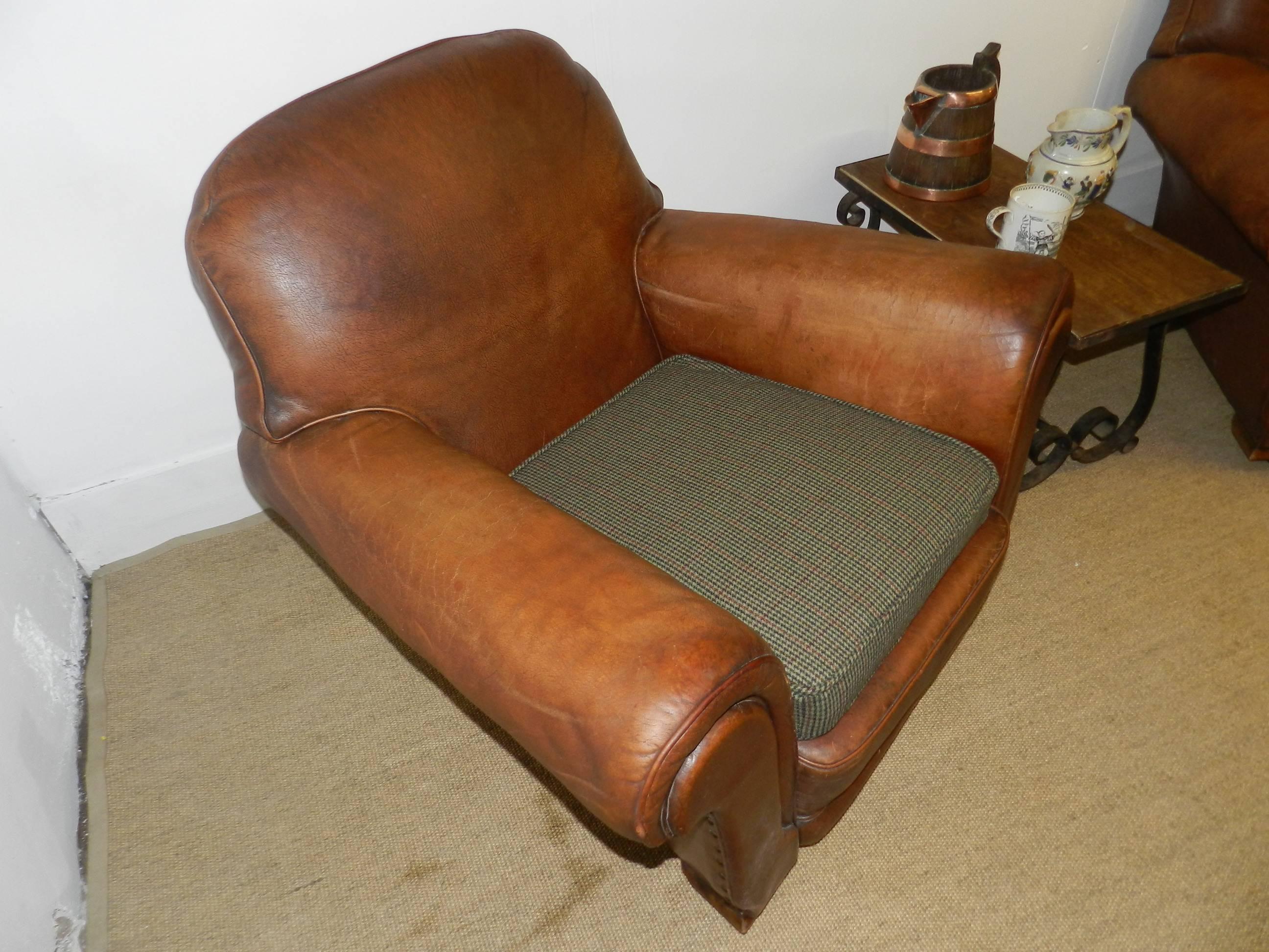 A pair of leather club chairs with Harris Tweed cushions.