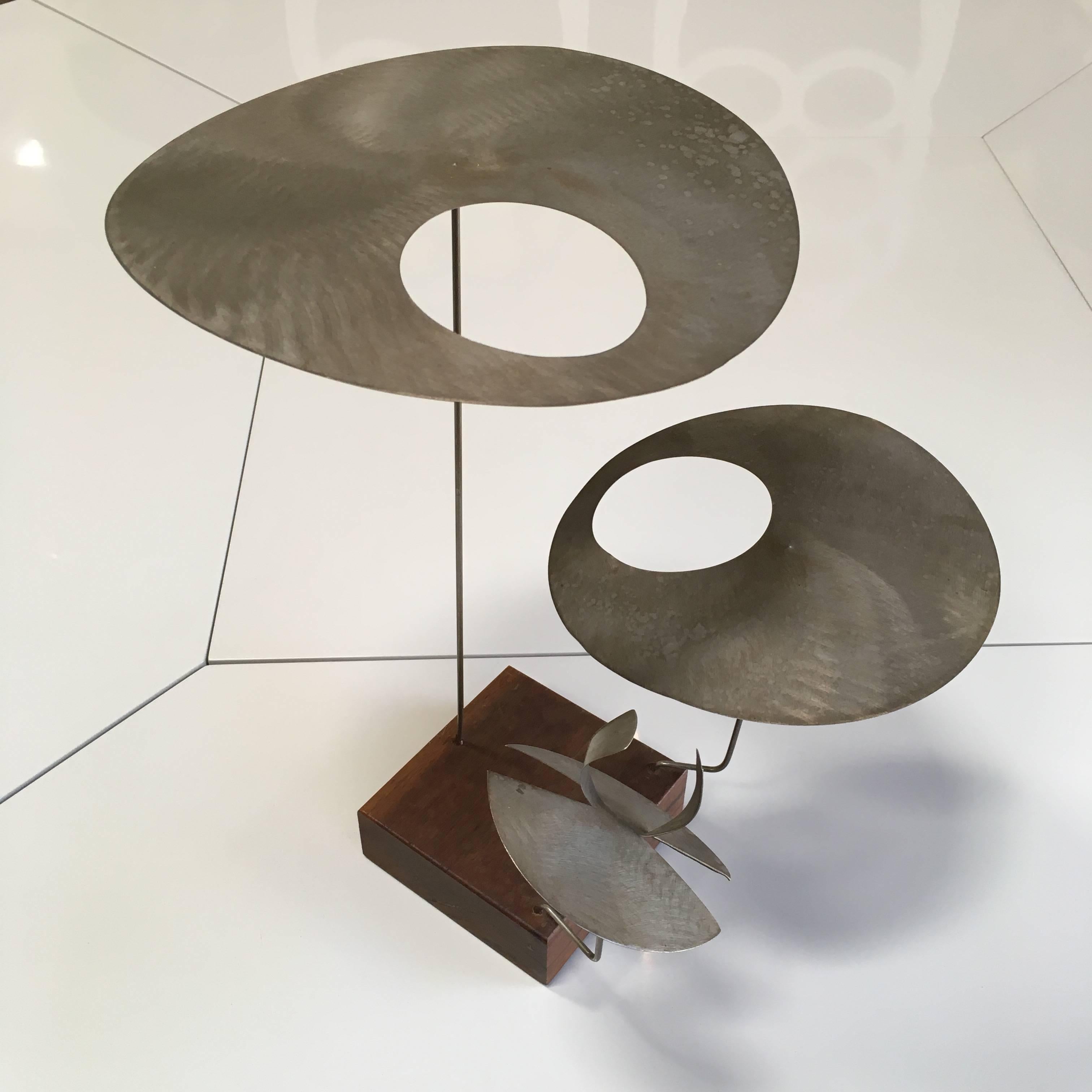 A fascinating kinetic sculpture. Biomorphic rotating metal discs cantilevered on metal rods and attached to square wooden base. Provenance accompanies.