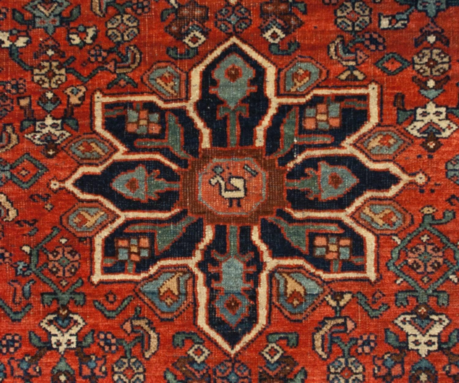 A beautiful late 19th century Persian Bidjar rug with a wonderful, slightly geometric in design, pattern with flowering scrolling vines on a rich crimson background. The central eight-lobed medallion is woven with deep indigo wool, with alternating