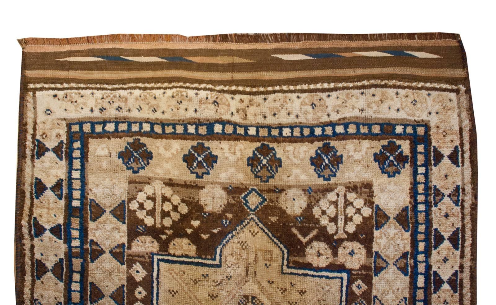 An incredible early 20th century Persian Gabbeh rug woven in undyed natural brown and beige wool accented with a few indigo dyed stripes. The two bold geometric medallions, each with a diamond motif in the center, are surrounded by a field of