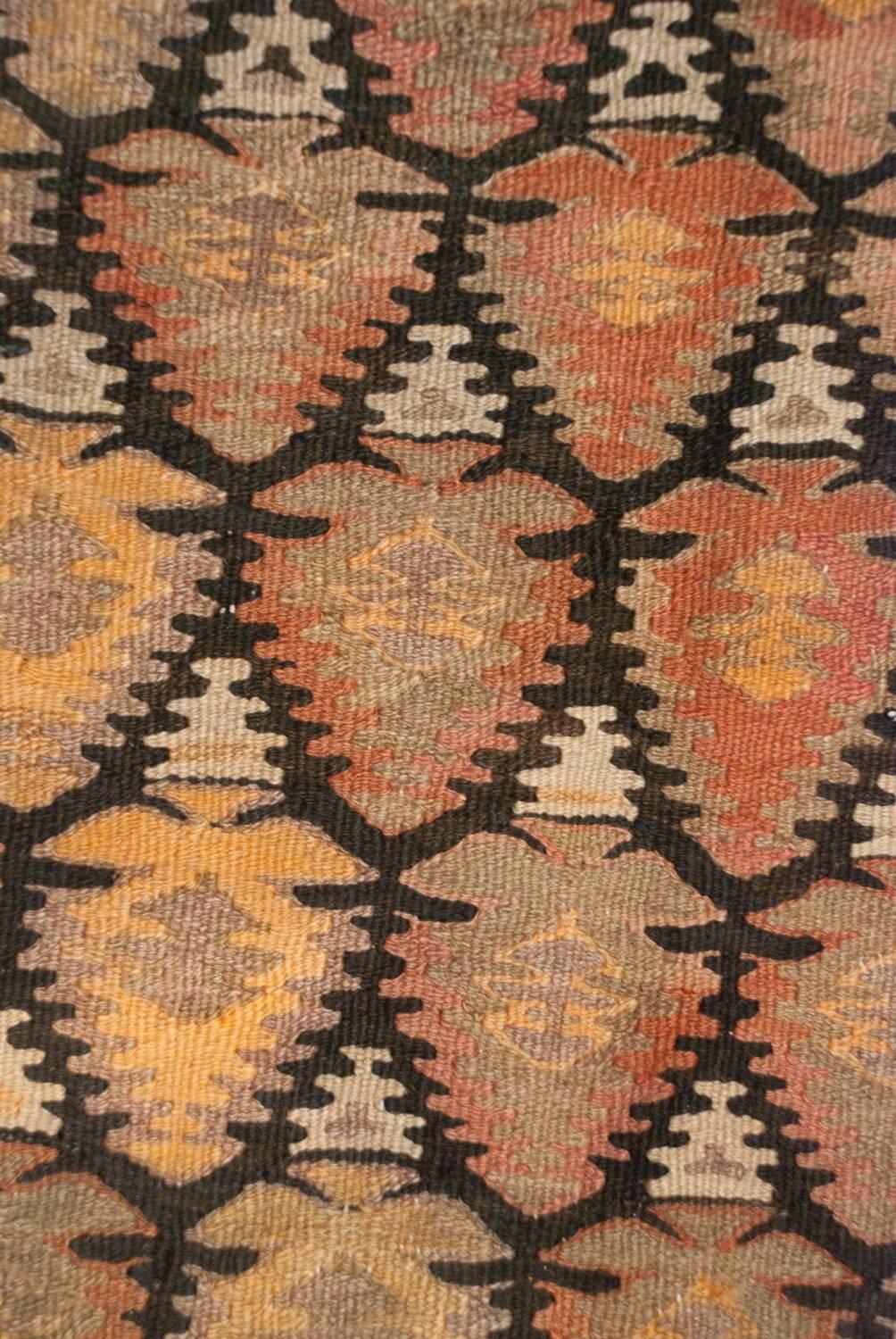 An early 20th century Persian Qazvin Kilim runner with a beautiful all-over multicolored stylized tree-of-life pattern on a black background. The border is comprised of three distinct multicolored geometric patterns.