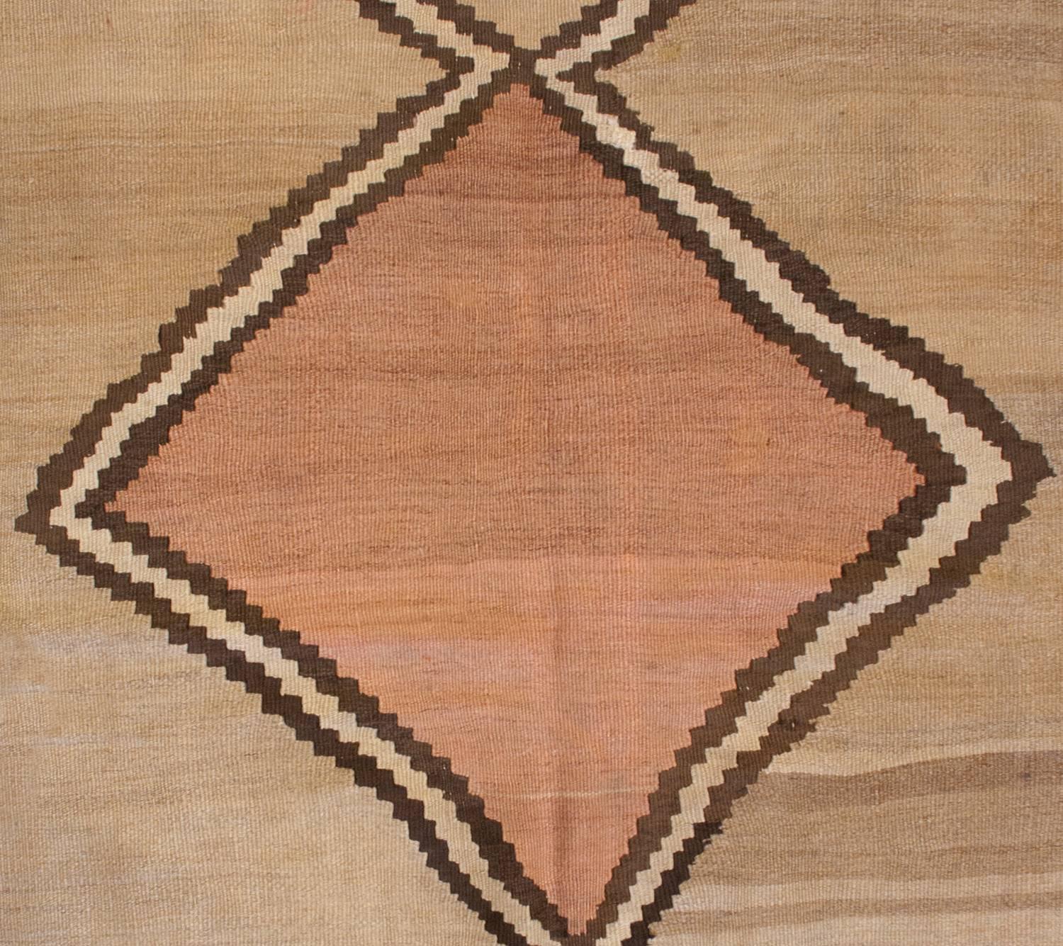 An early 20th century Persian Shahsavan Kilim rug with an incredible large-scale zig-zag pattern that runs down the center. A large pale red diamond is centrally positioned. The rest of the rug is woven in natural, undyed, wool. The border is