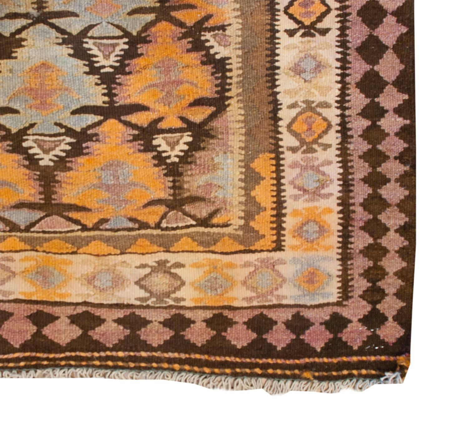 A wonderful early 20th century Persian Qazvin Kilim runner with a skillfully woven tree-of-life pattern with each tree having multicolored layers. Between the trees are white triangle forms. The border is comprised of three distinct patterns. The