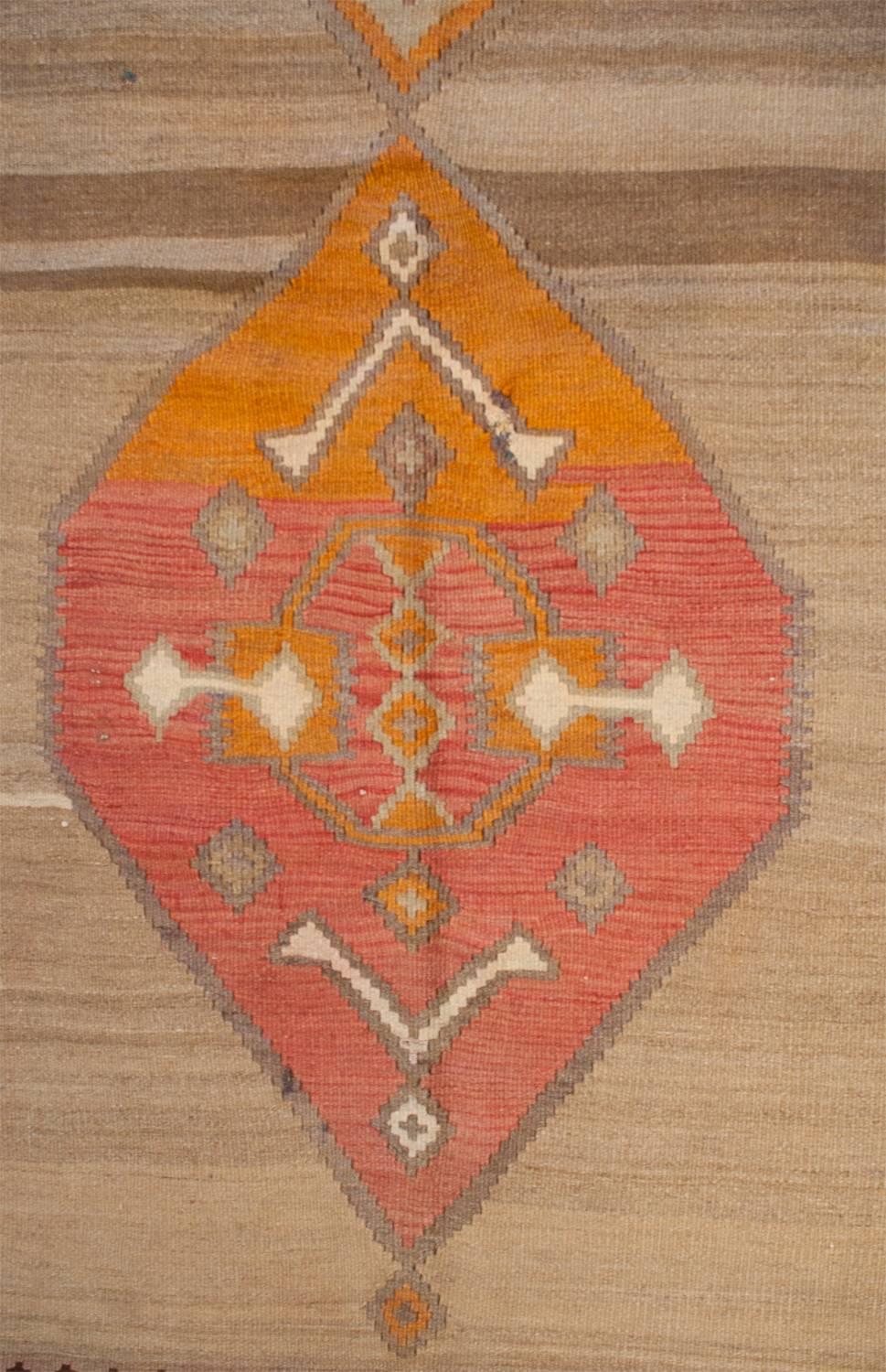 A fantastic early 20th century Shahsavan Kilim rug with two wonderful diamond medallions. One is woven in a brilliant salmon and rust orange dyed wool. The other is woven with the same rust orange highlighting some of the geometric designs. The