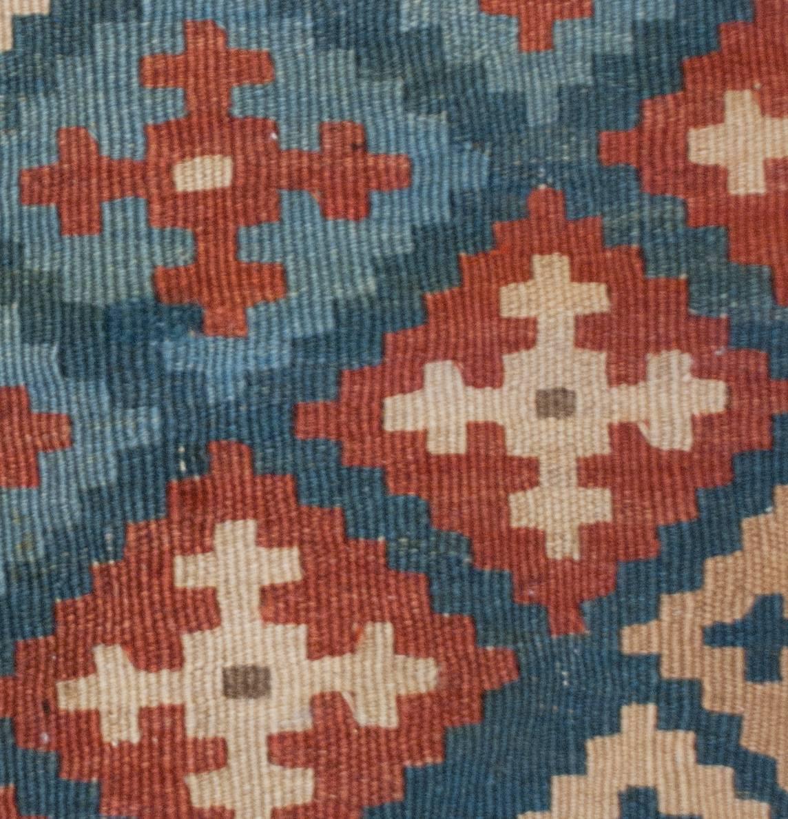 A wonderful early 20th century Shahsavan Kilim rug with a traditional multi-colored crimson, sage green, indigo, and pink diamond pattern composed in a diagonal stripe running across the field. The border is wide with hexagonal forms dotting the