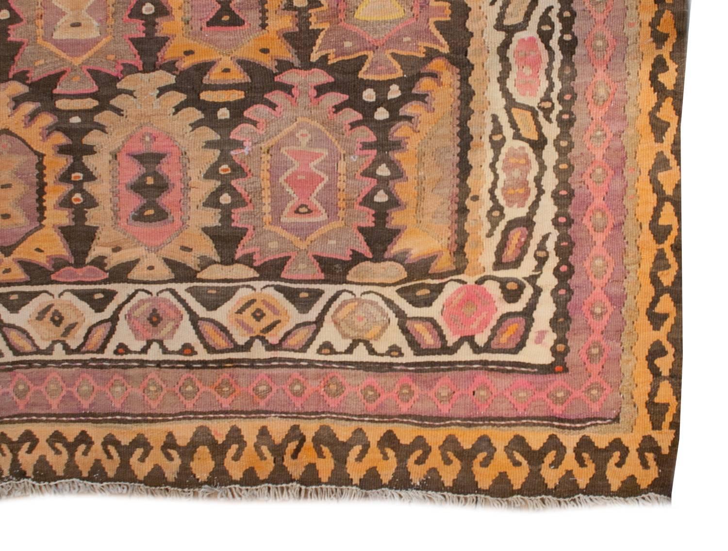 An early 20th century Persian Qazvin Kilim rug with a fantastic stylized multicolored tree-of-life pattern with woven in rich pink, gold, brown and cream wool. The border consists of three distinct patterns, one with stylized blossoms and vines, one