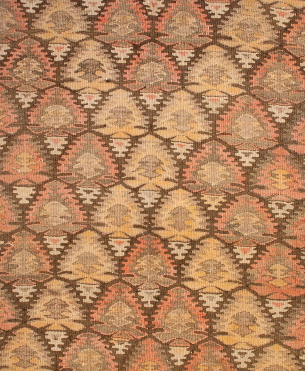 An early 20th century Persian Qazvin Kilim runner with a beautiful all-over multicolored stylized tree-of-life pattern on a black background. The trees are colored in a way that they create a gold zigzag pattern across the field. The border is wide