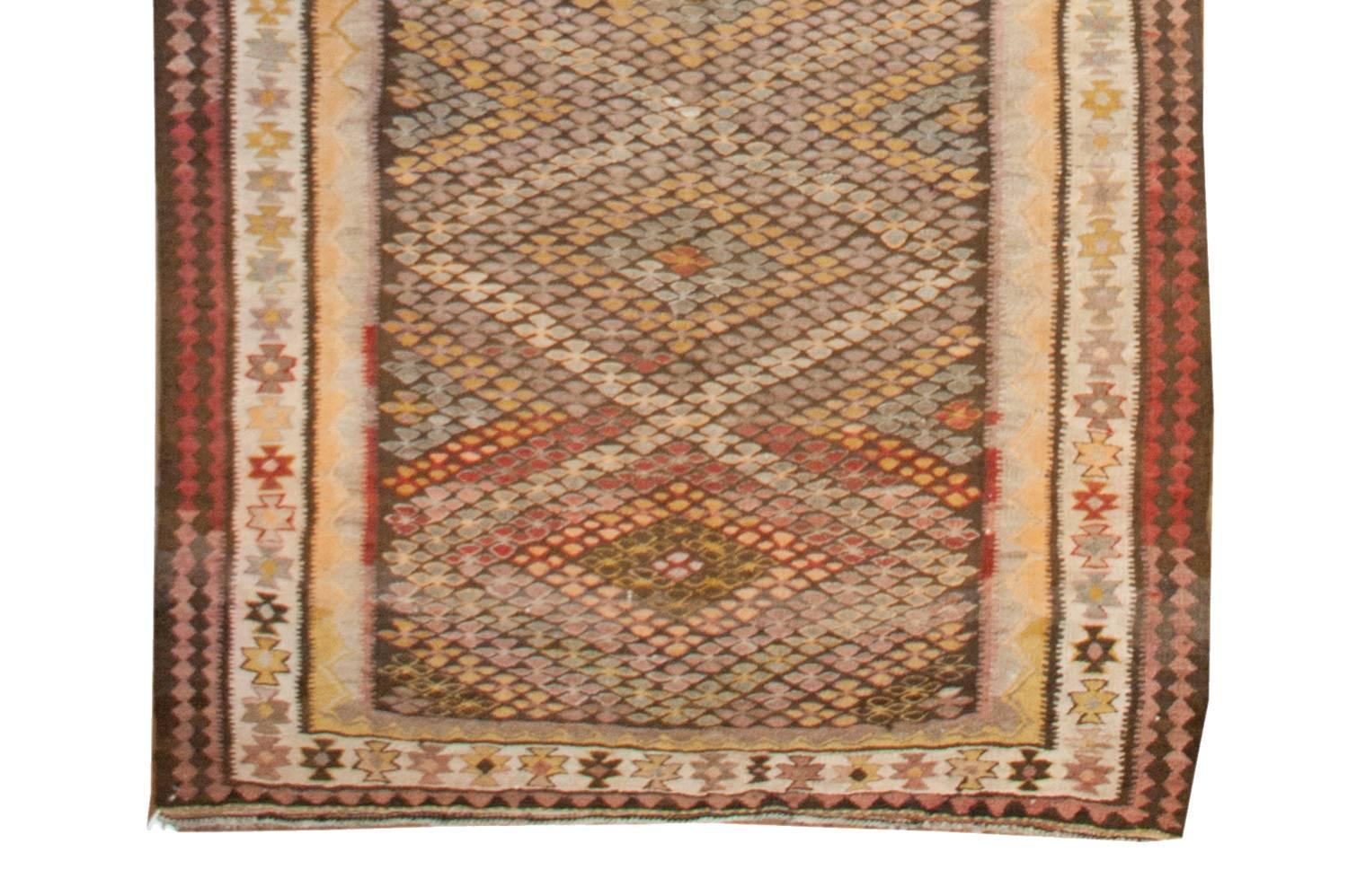 An exquisite Qazvin Kilim runner with an incredible and unique multicolored four-lobed floral pattern creating a diamond pattern across the field. The border is composed of three distinct patterns, with a central white stripe covered with