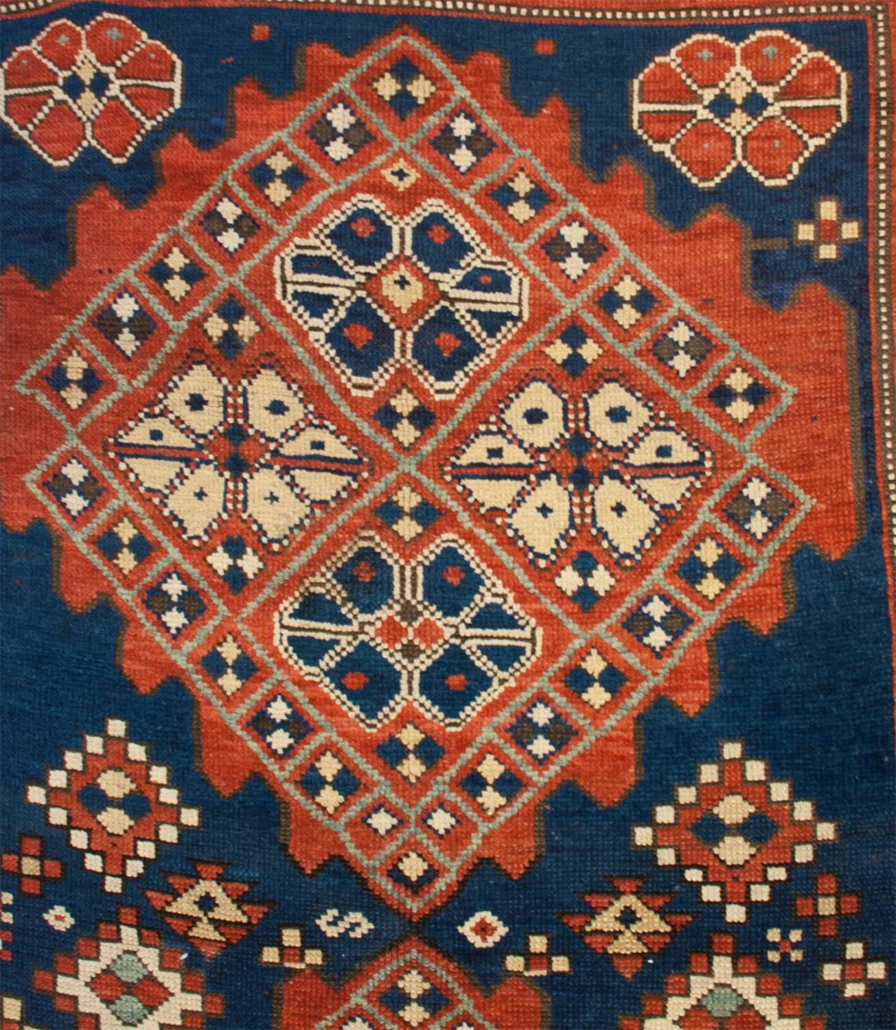 An exceptional and notable late 19th century Persian Kazak rug with two large diamond medallions each composed with four stylized flowers woven in indigo and natural wool surrounded by check-board patterned squares, all resting on an interesting