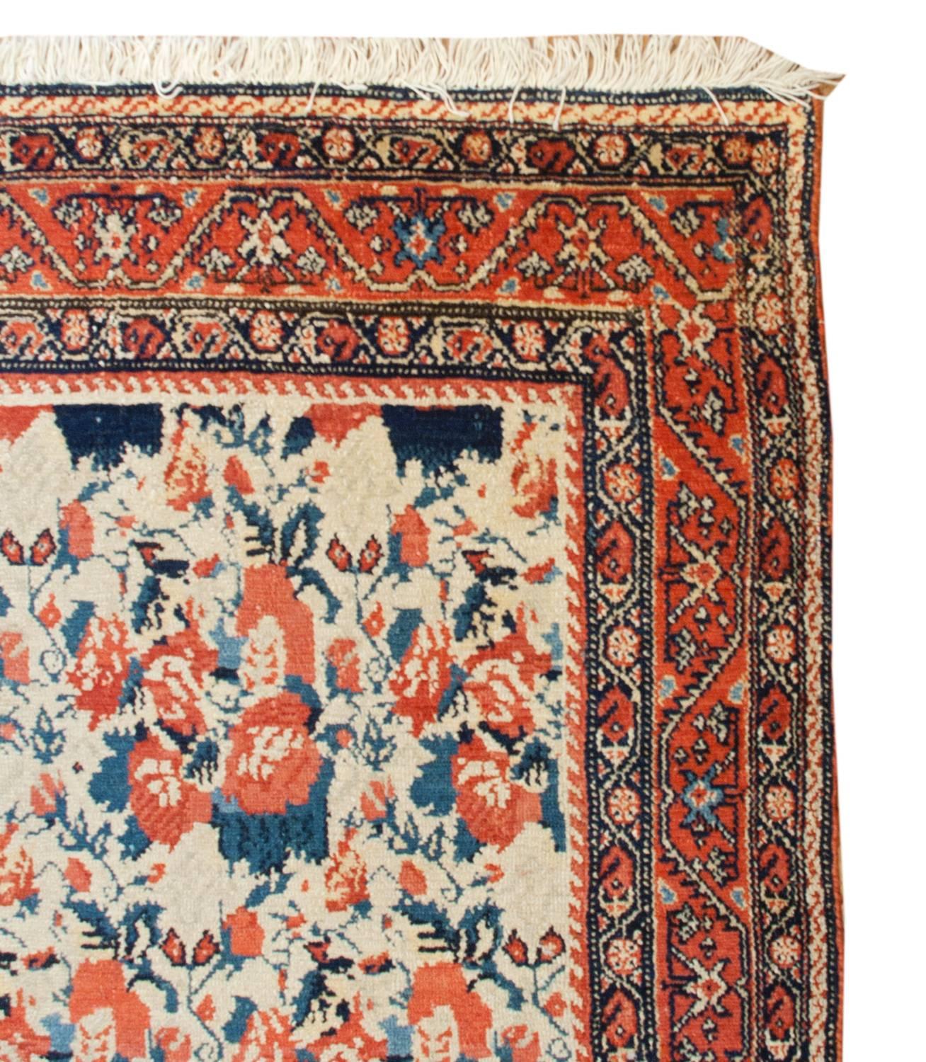 An outstanding late 19th century Persian Senneh rug with an incredible masterfully woven large-scale repeated floral pattern woven in crimson and indigo on a natural wool background. The border is fantastic with three distinct floral and vine